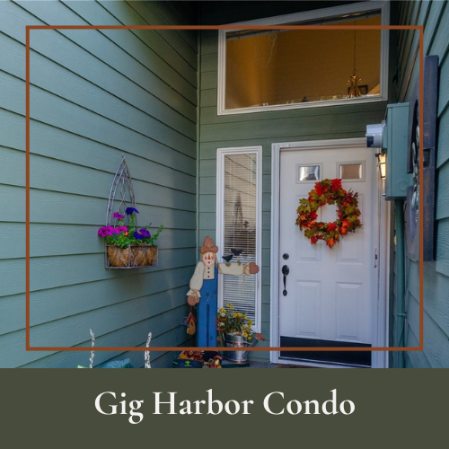 Front porch of a condo with a white door decorated with a fall wreath, a vertical mirror, a flower basket, and a scarecrow figure, with a window above.
