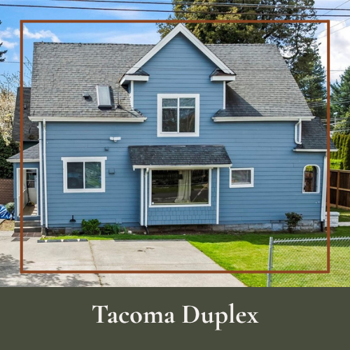 Front view of a blue Tacoma Duplex house with a gray roof, multiple windows, a small front porch, and a garden area with grass and a chain-link fence.