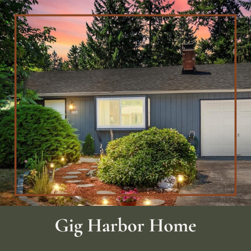 Front of a suburban home with a well-maintained garden, illuminated pathway, blue exterior walls, large window, and attached garage, during sunset.