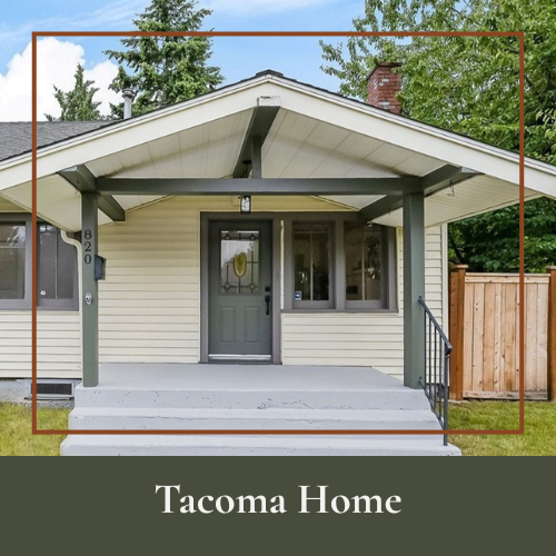 Front view of a Tacoma home with a front porch, stairs, door, and windows, surrounded by trees and a wooden fence.