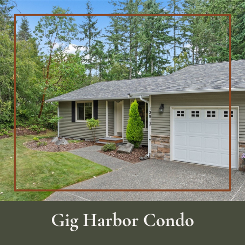 Front view of a suburban condo with gray siding, a white garage door, small front porch, green plants, and a well-maintained lawn with trees in the background.