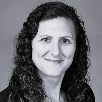 Black and white portrait of a woman with long, curly hair, smiling at the camera.
