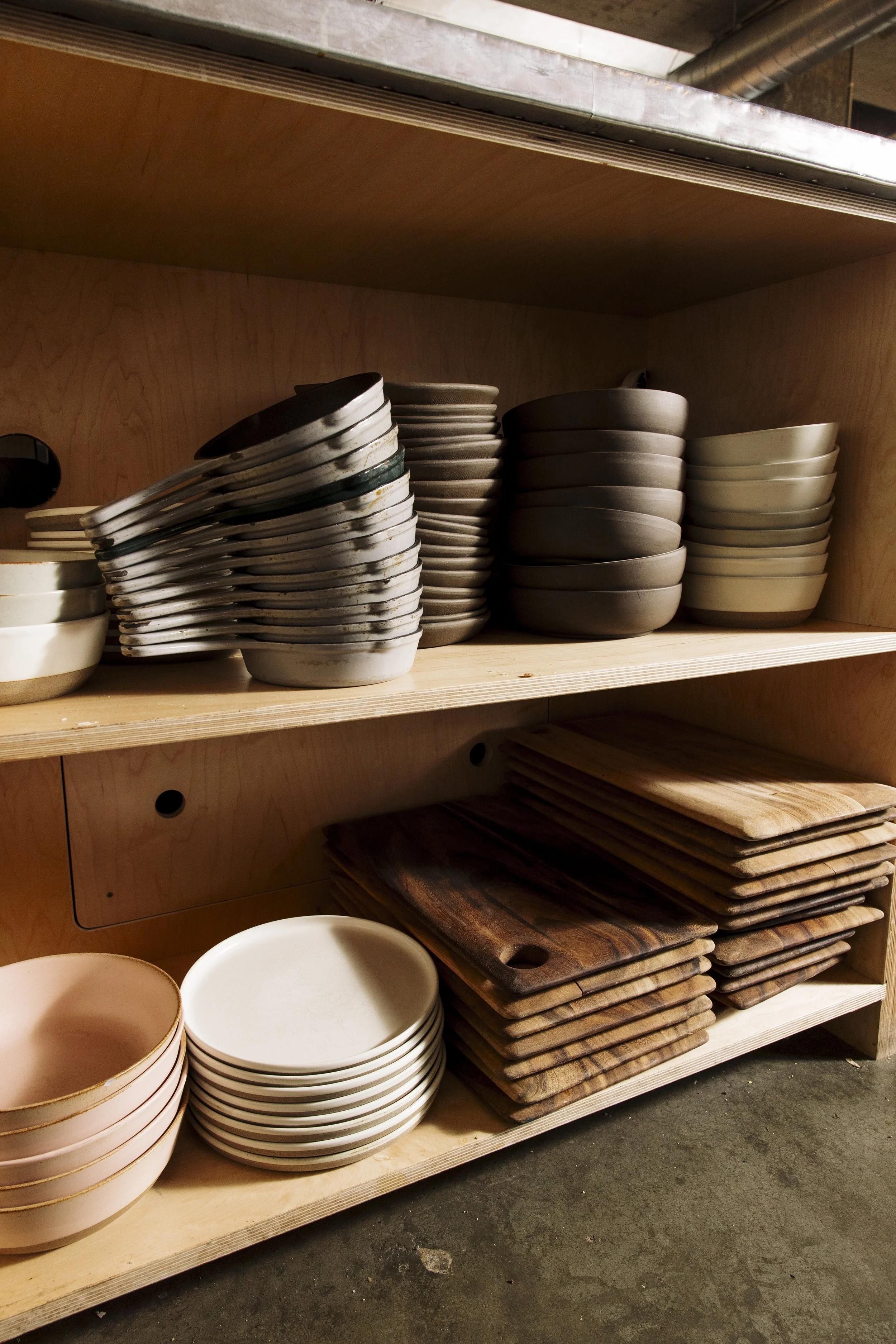 Shelves filled with stacked bowls, plates, and wooden cutting boards.