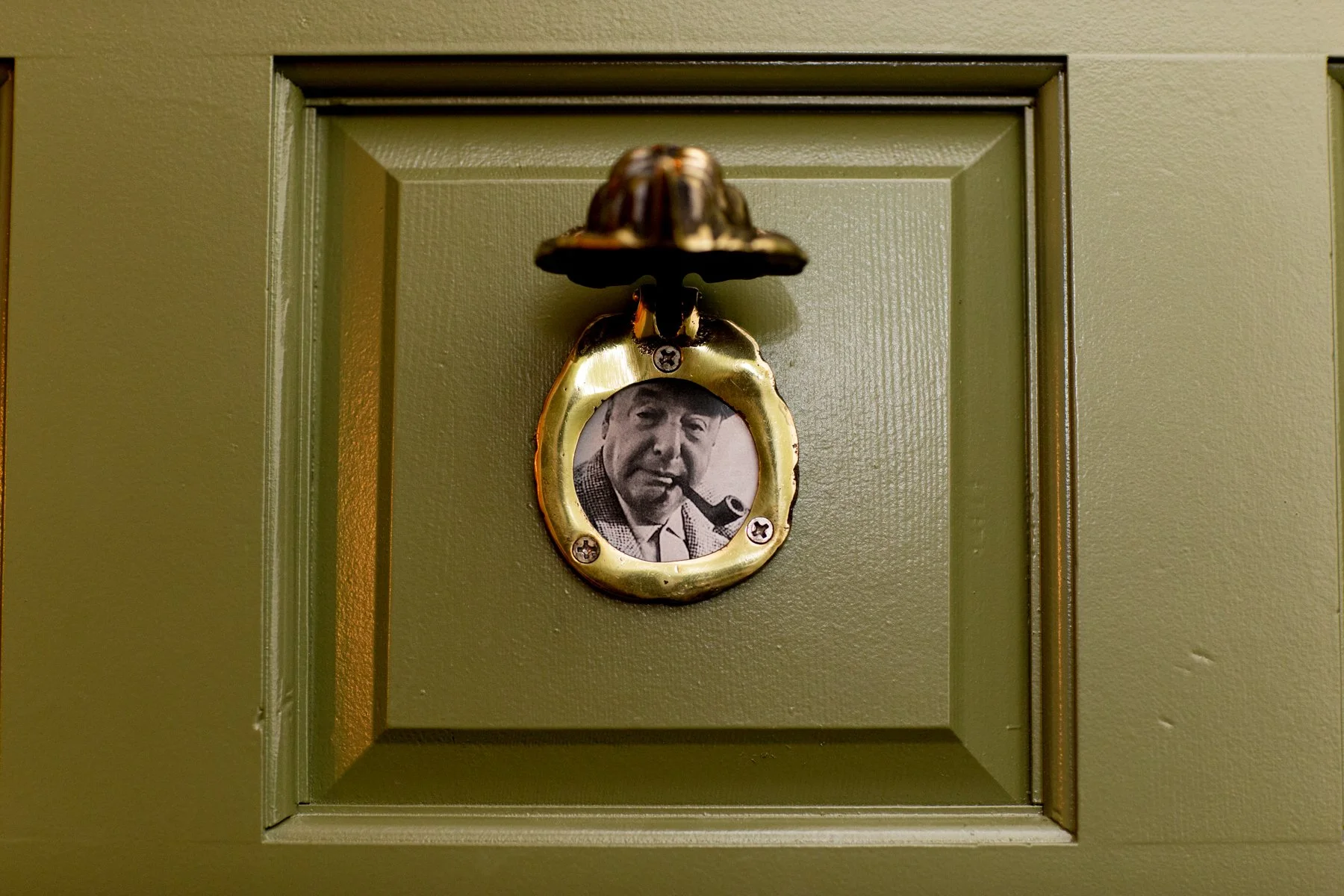 A door with a decorative metal plaque featuring a black and white photo of a man smoking a pipe.
