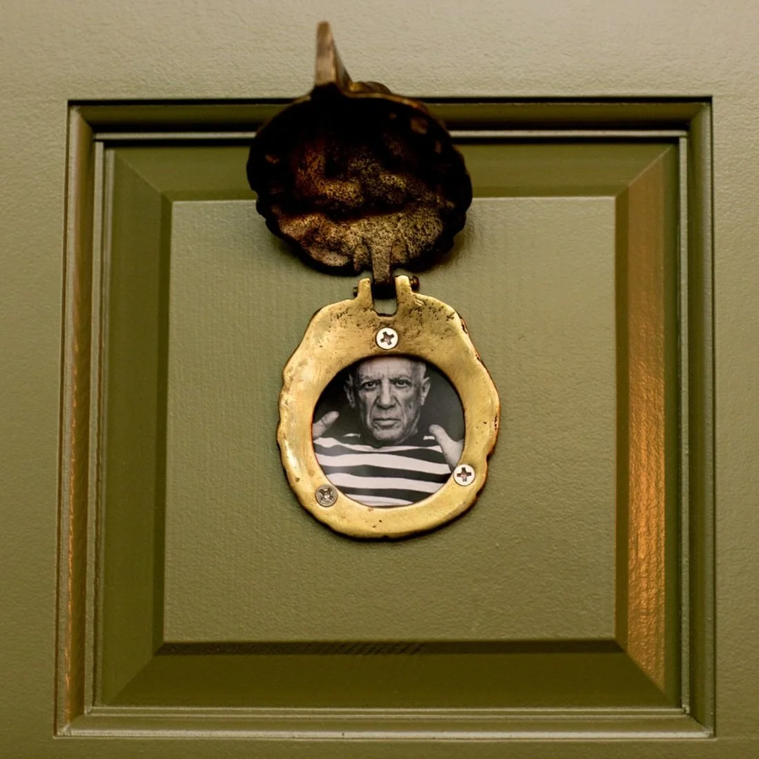 Decorative wall picture frame with a black and white photograph of an older man in a striped shirt, set in a green shadow box with a leaf-shaped top decoration.
