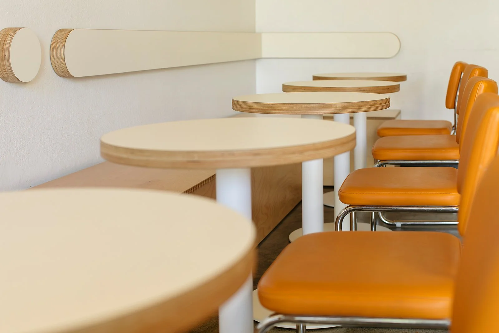 Empty cafe with round beige tables and orange chairs