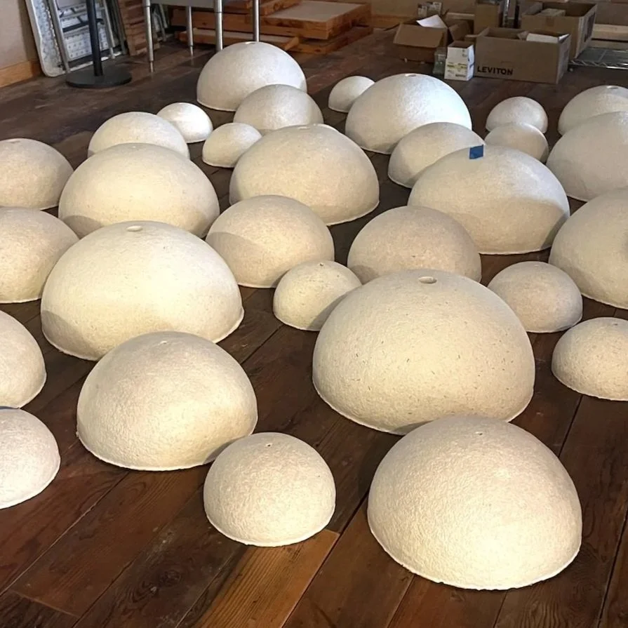 Collection of white, dome-shaped objects of various sizes arranged on a wooden floor, with boxes and shelves in the background.