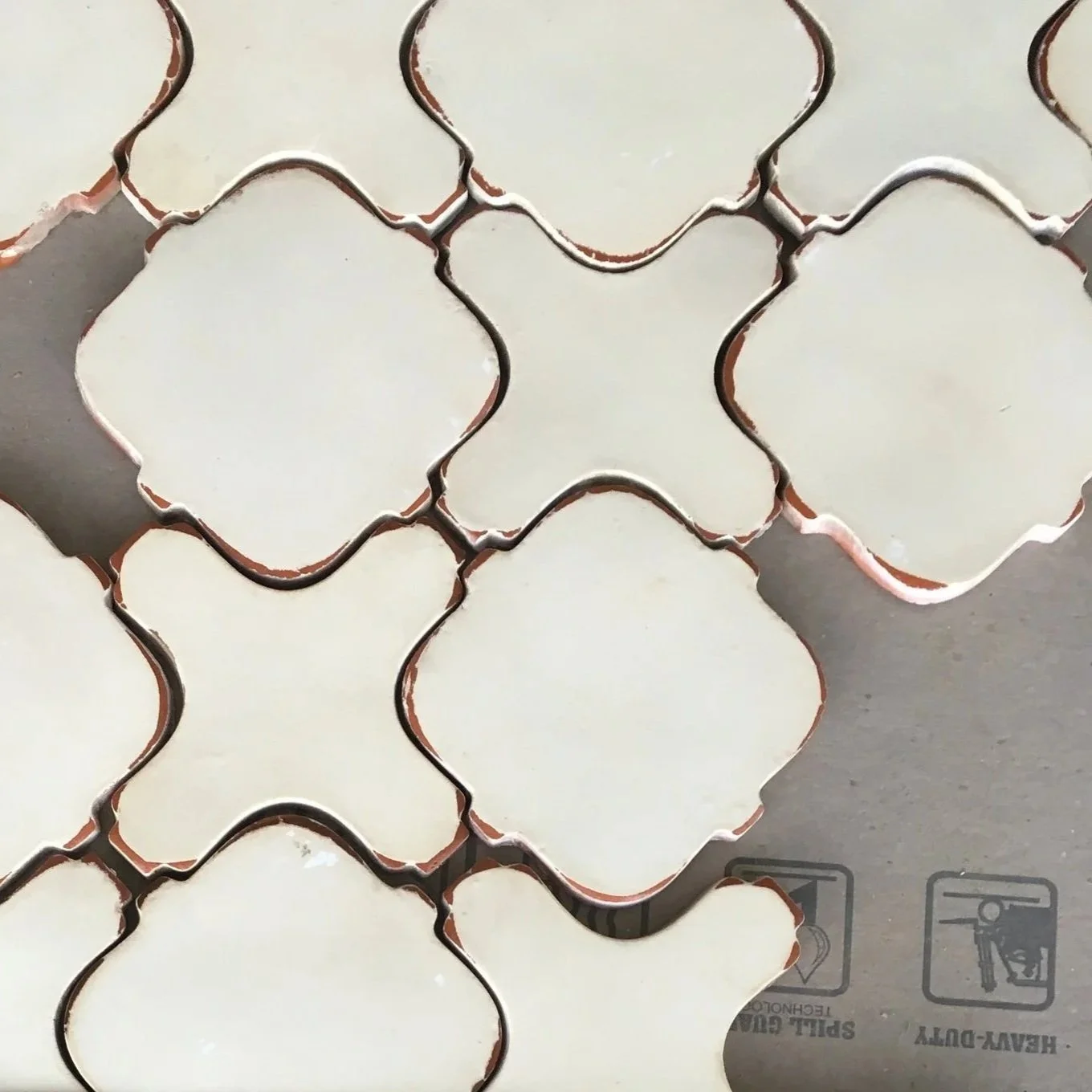 A collection of white ceramic or porcelain tiles with scalloped edges, arranged on a surface.