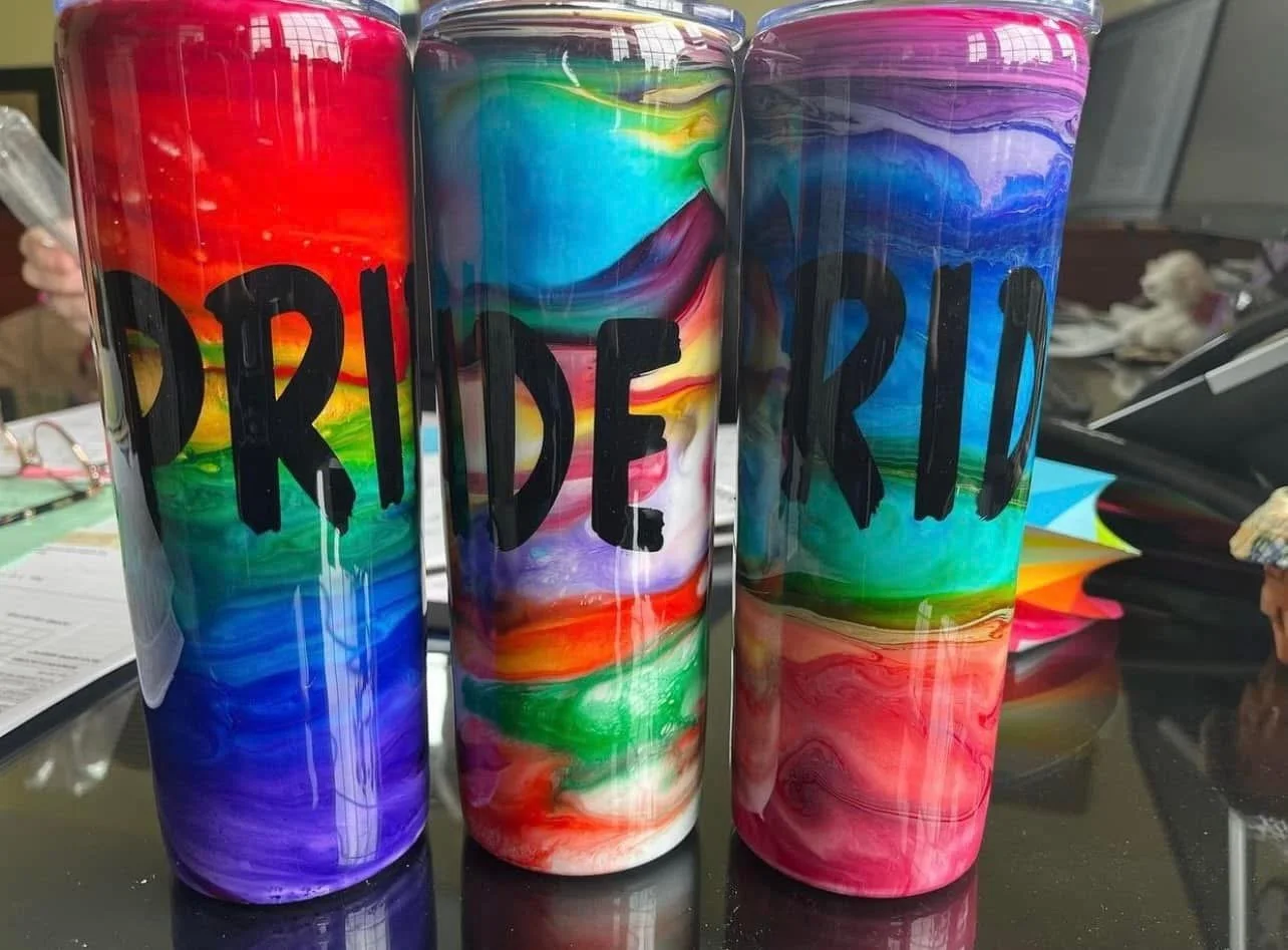 Three colorful metal cans with a marbled rainbow pattern and the word