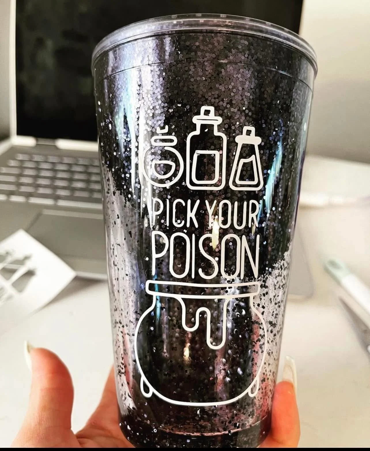 A clear tumbler with black glitter and a white design featuring medicine bottles and the phrase 'Pick Your Poison' with a dripping liquid illustration.