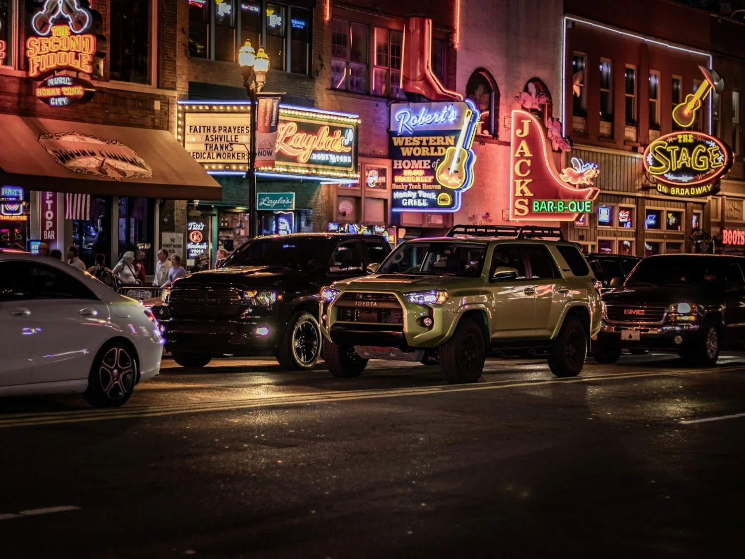 Lower Broadway in Nashville at night with neon honky-tonk signs, where mobile surveillance follows the night