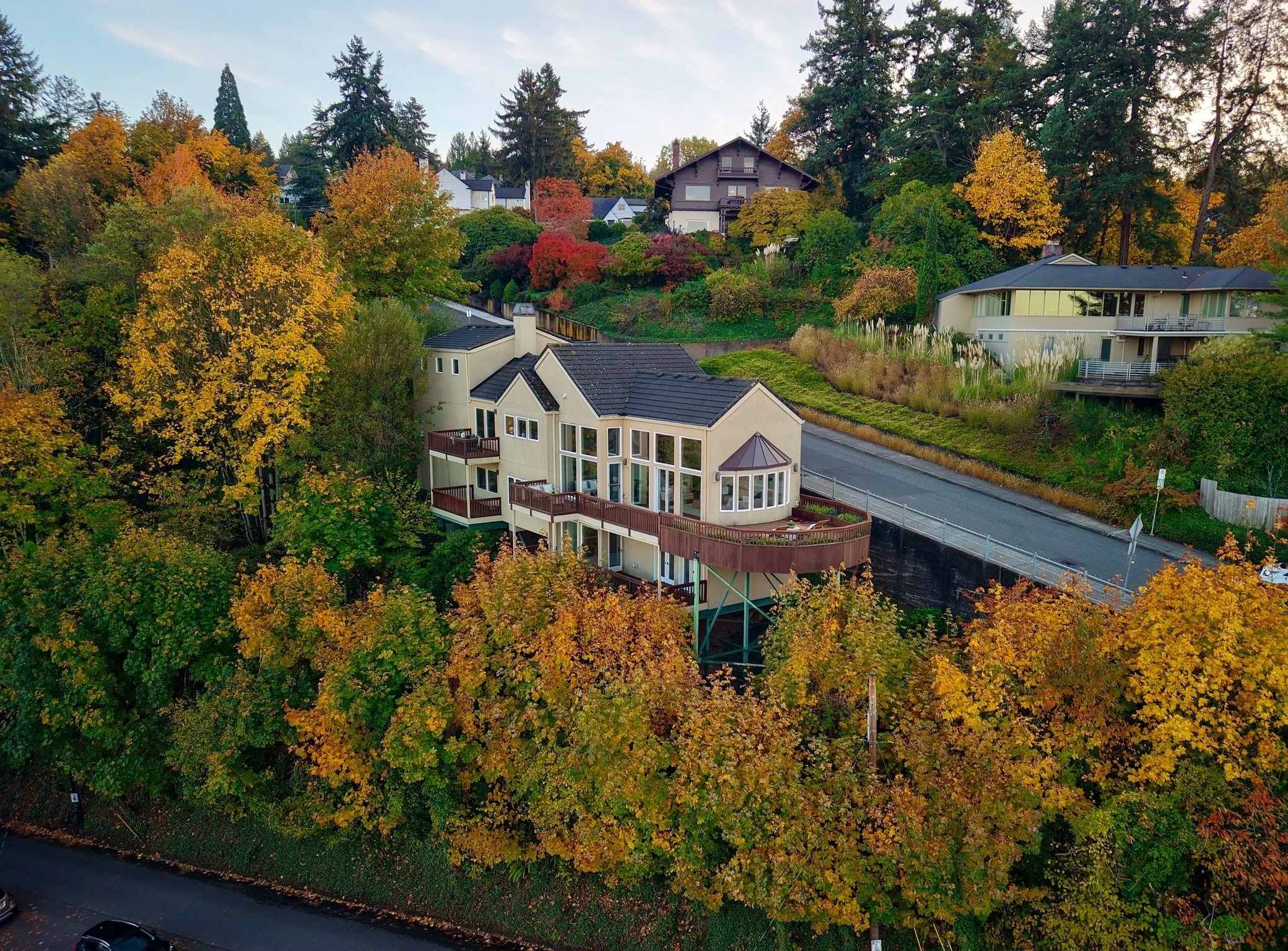An aerial view of a neighborhood with houses surrounded by trees displaying fall colors.