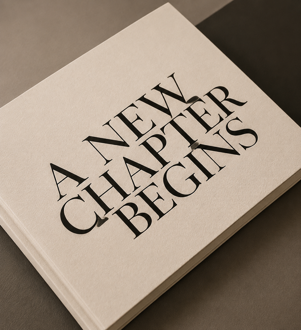 A white book cover with the title 'A New Chapter Begins' in large black serif font, placed on a gray surface.