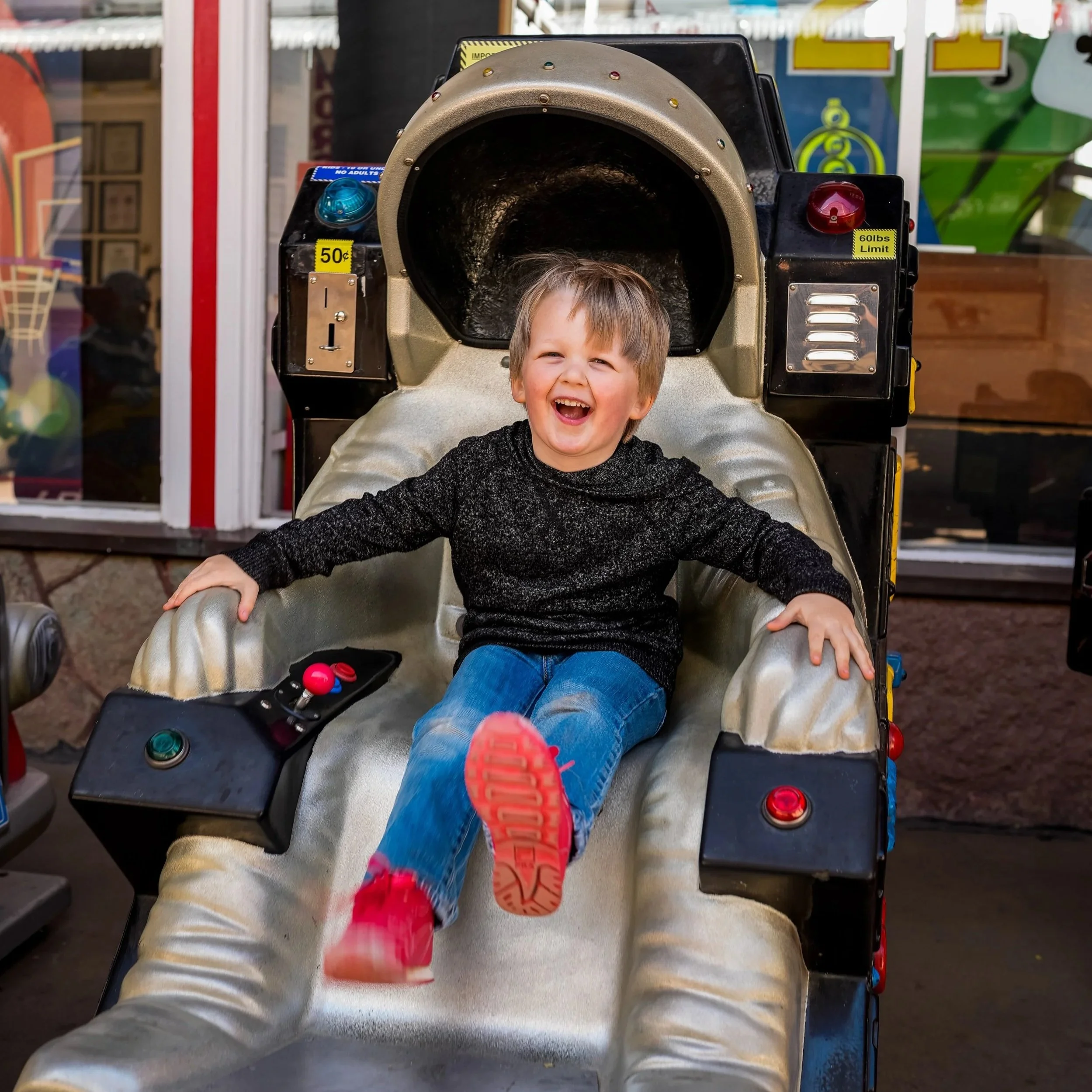 A young boy with a big smile sitting in a coin-operated amusement ride in downtown Manitou Springs, Colorado.