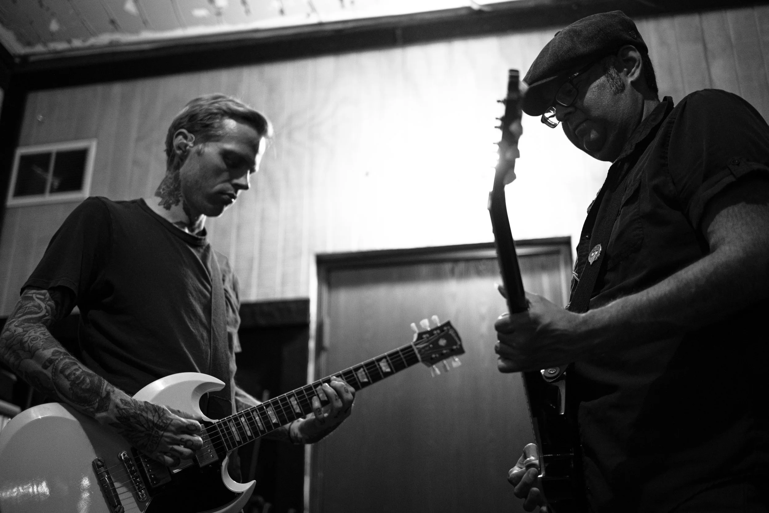 Two men are engaged in a music session in a dimly lit room.