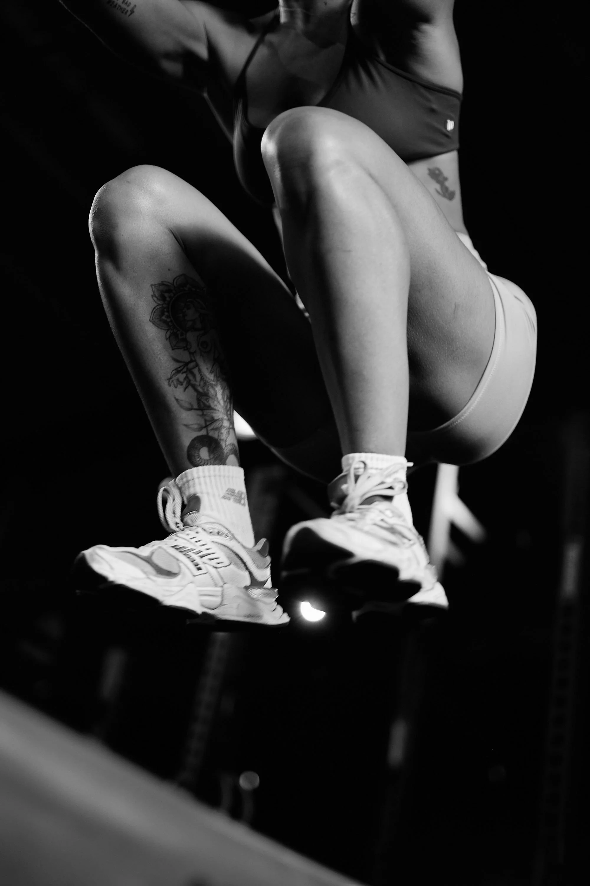 Close-up of a person wearing athletic shoes and shorts, jumping onto a block