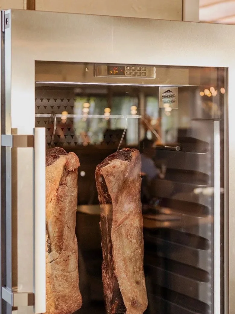 Two large slabs of beef being cooked in a commercial oven or smoker.