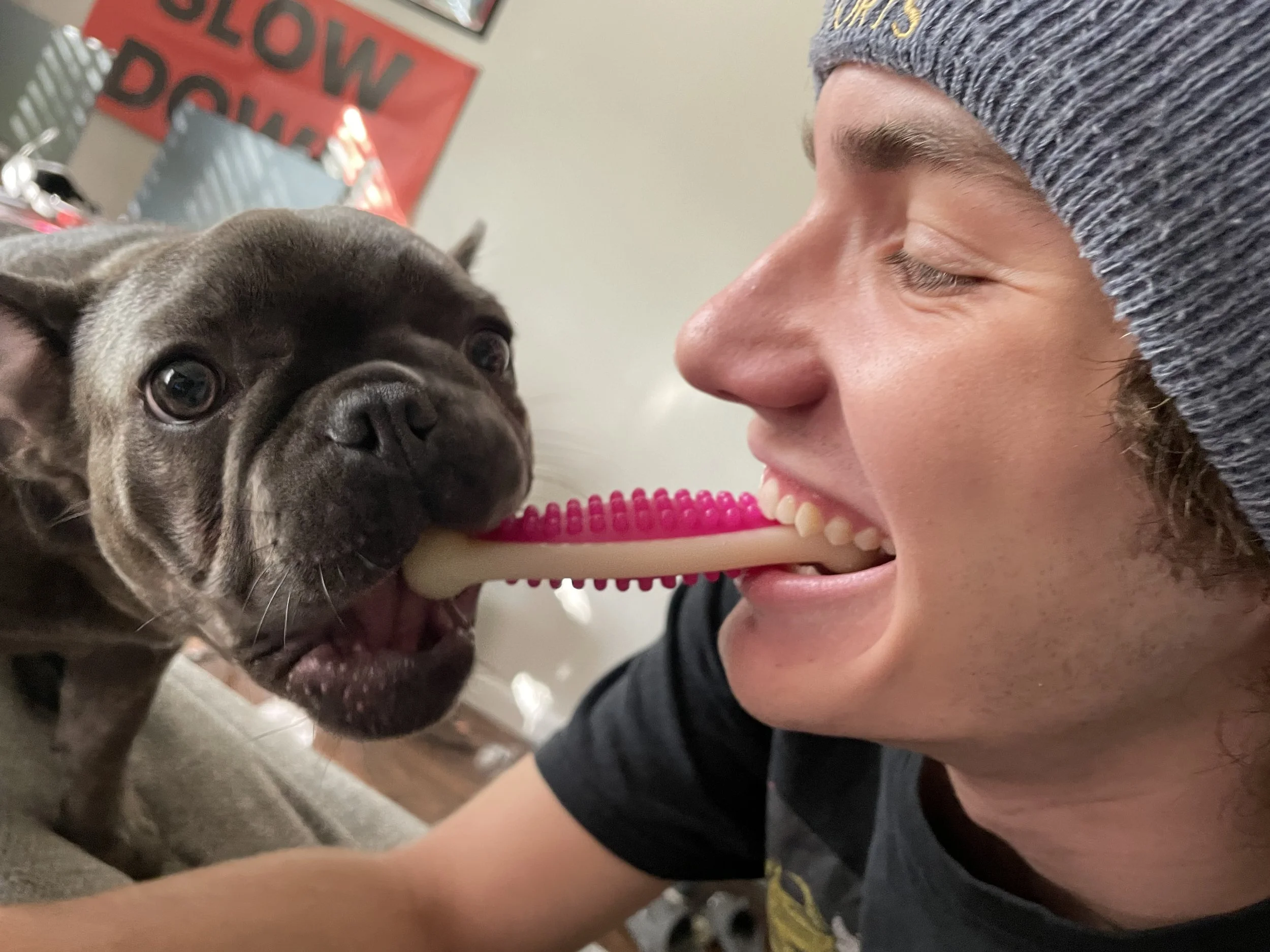 A young man smiling with eyes closed closely facing a small puppy dog.