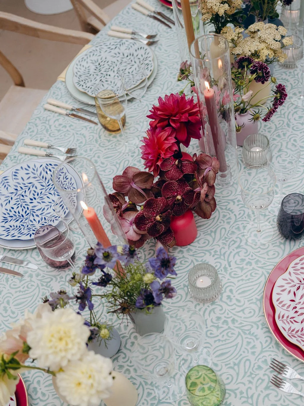 A decorated table with floral arrangements, candles, and colorful plates set for a meal.