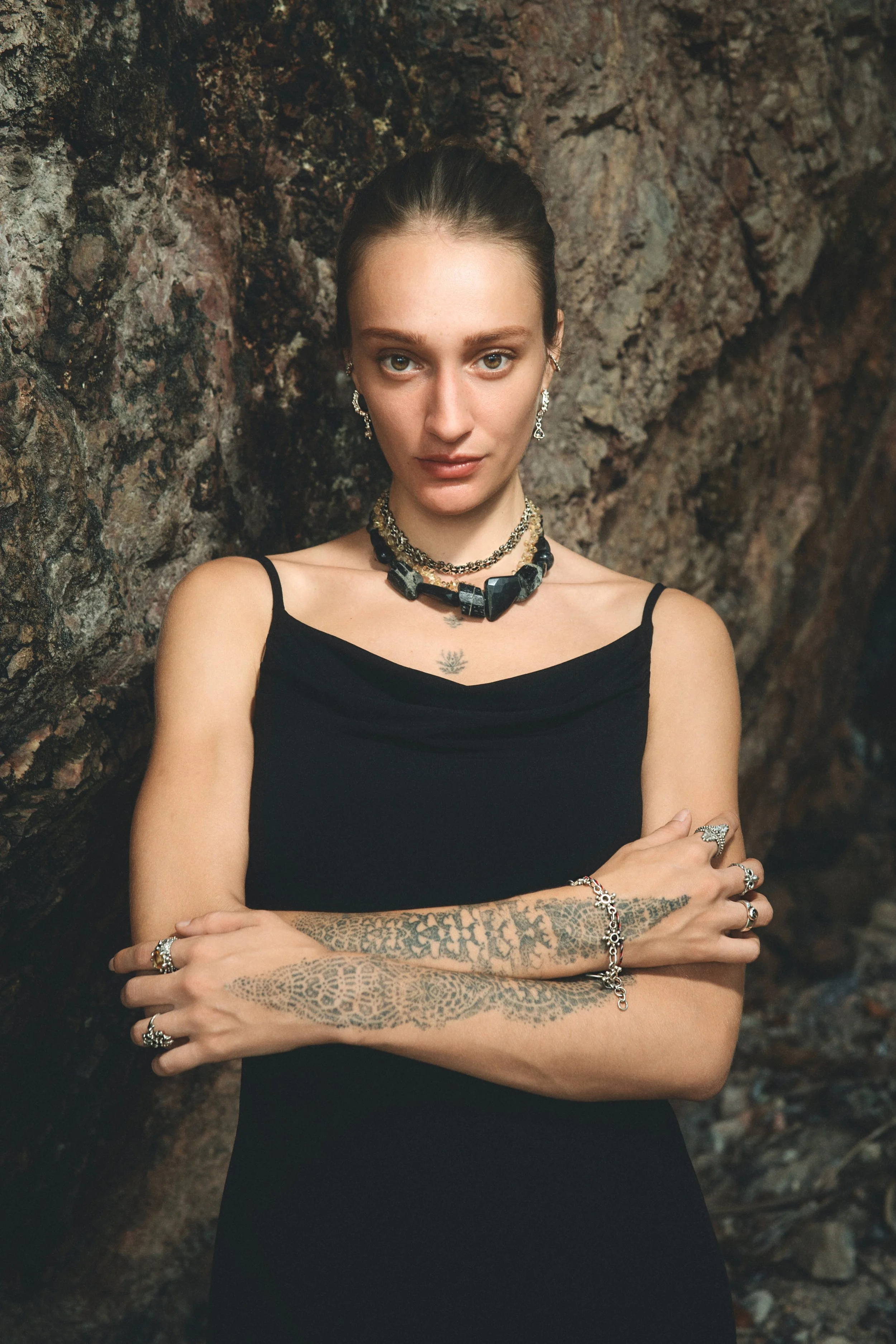 Model wearing handmade silver necklaces, rings, and earrings by OJAS Studio against a dark background.