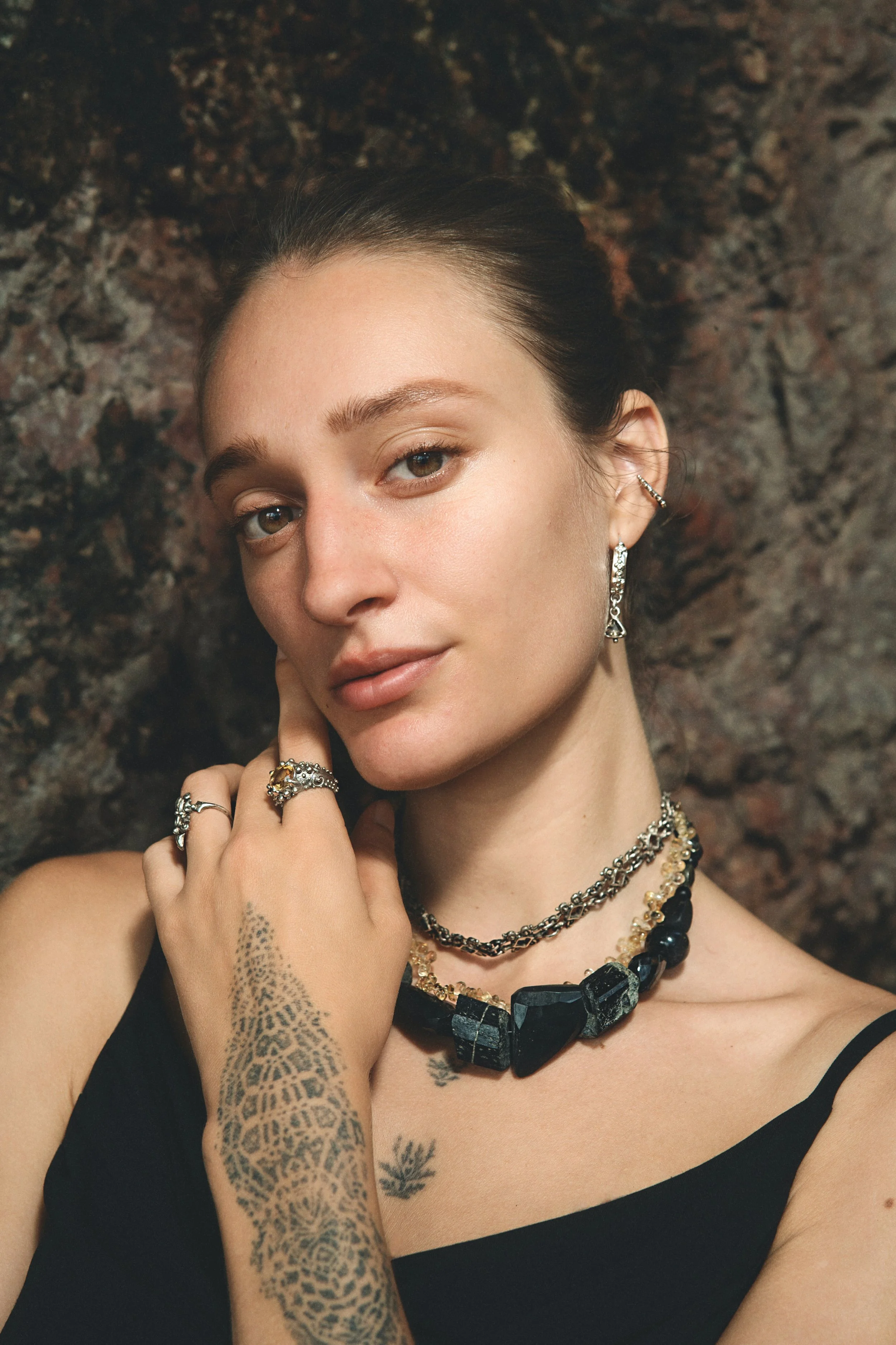 Model wearing handmade silver necklaces, rings, and earrings by OJAS Studio against a dark background.