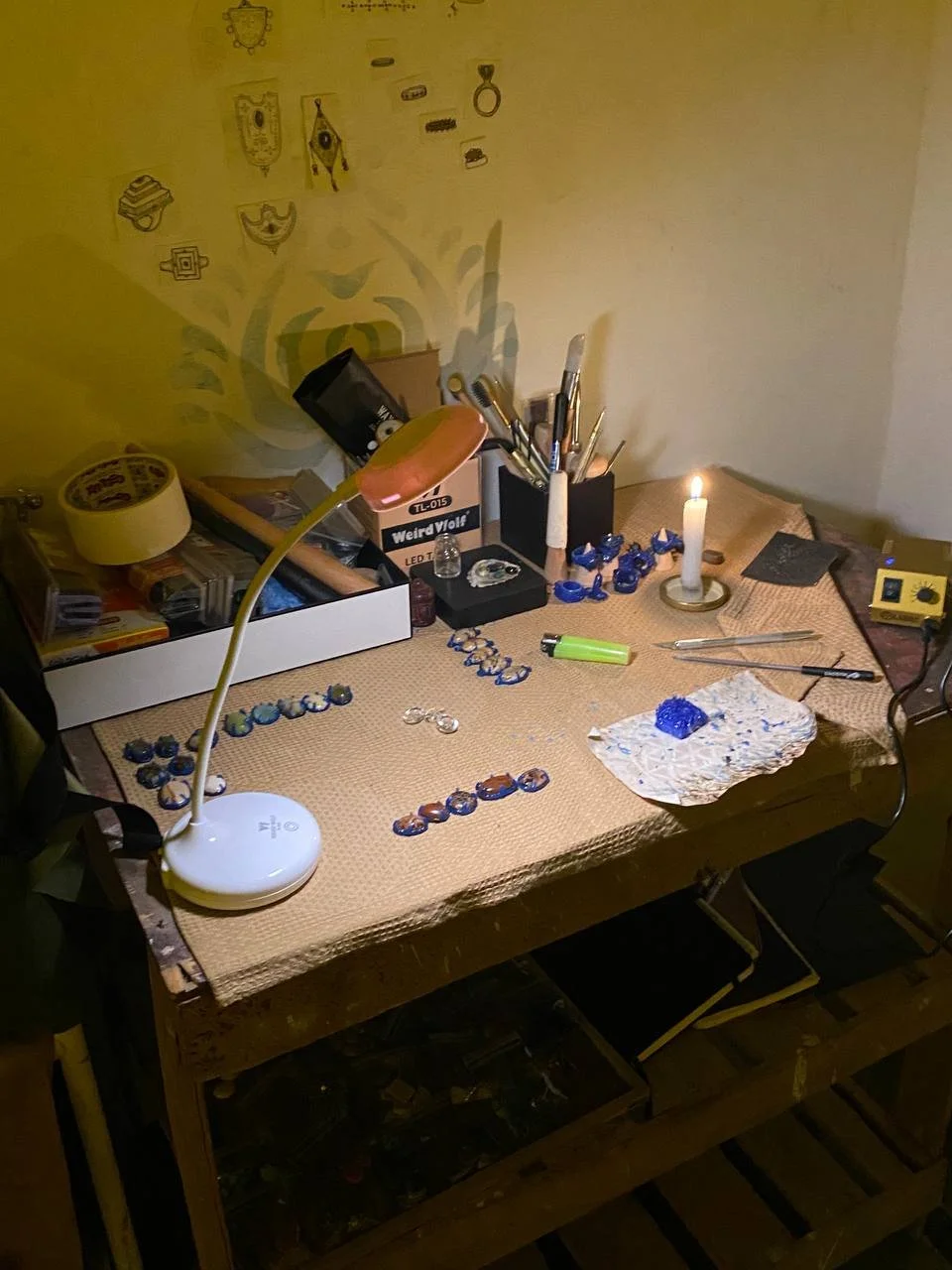 OJAS Studio handmade jewelry workbench — sterling silver pieces and tools by candlelight