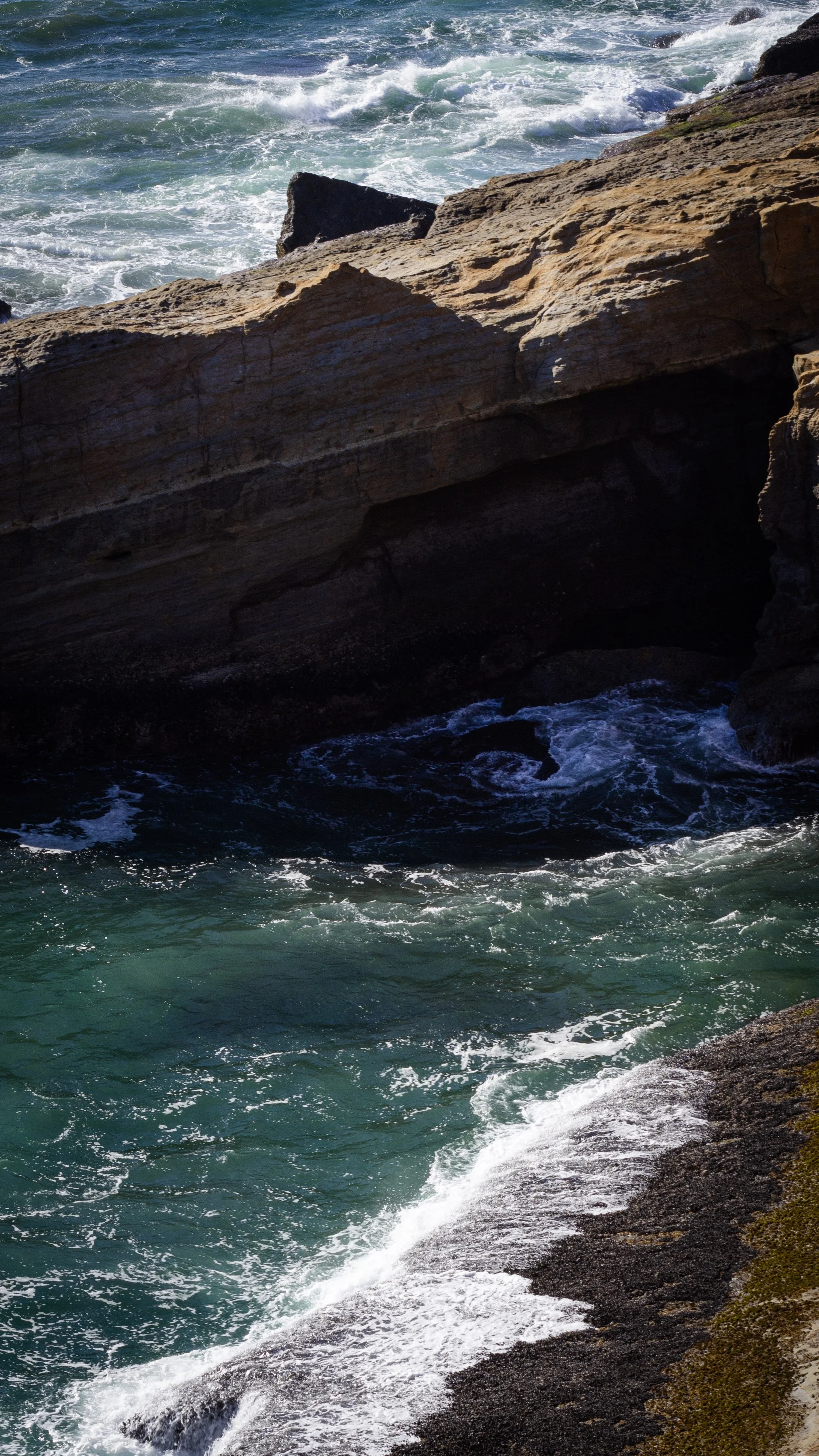 Rocky shoreline with waves crashing against the rocks and water.
