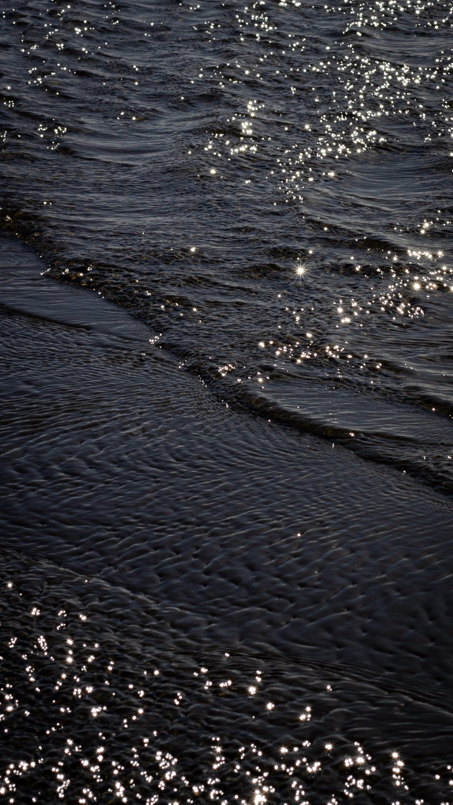 Close-up of water with sunlight reflecting off the surface, creating sparkling highlights.