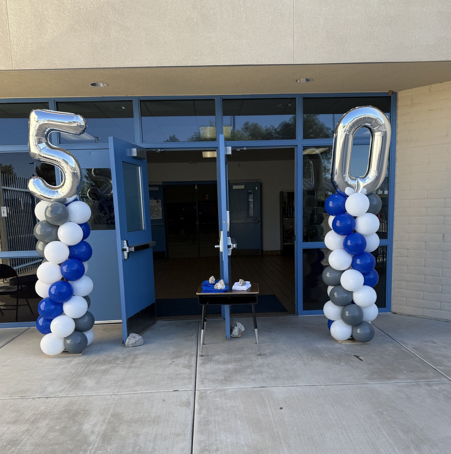 Decorative balloons spelling out '50' at the entrance of a building.