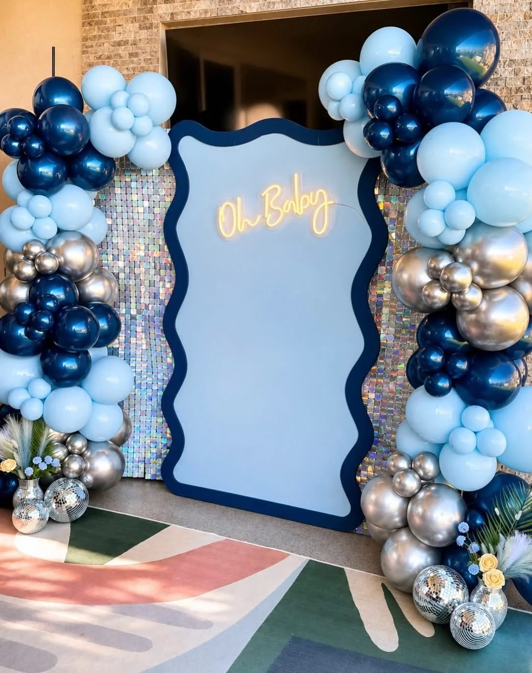 Disco baby shower featuring a wavy wall and silver sparkle panels. 