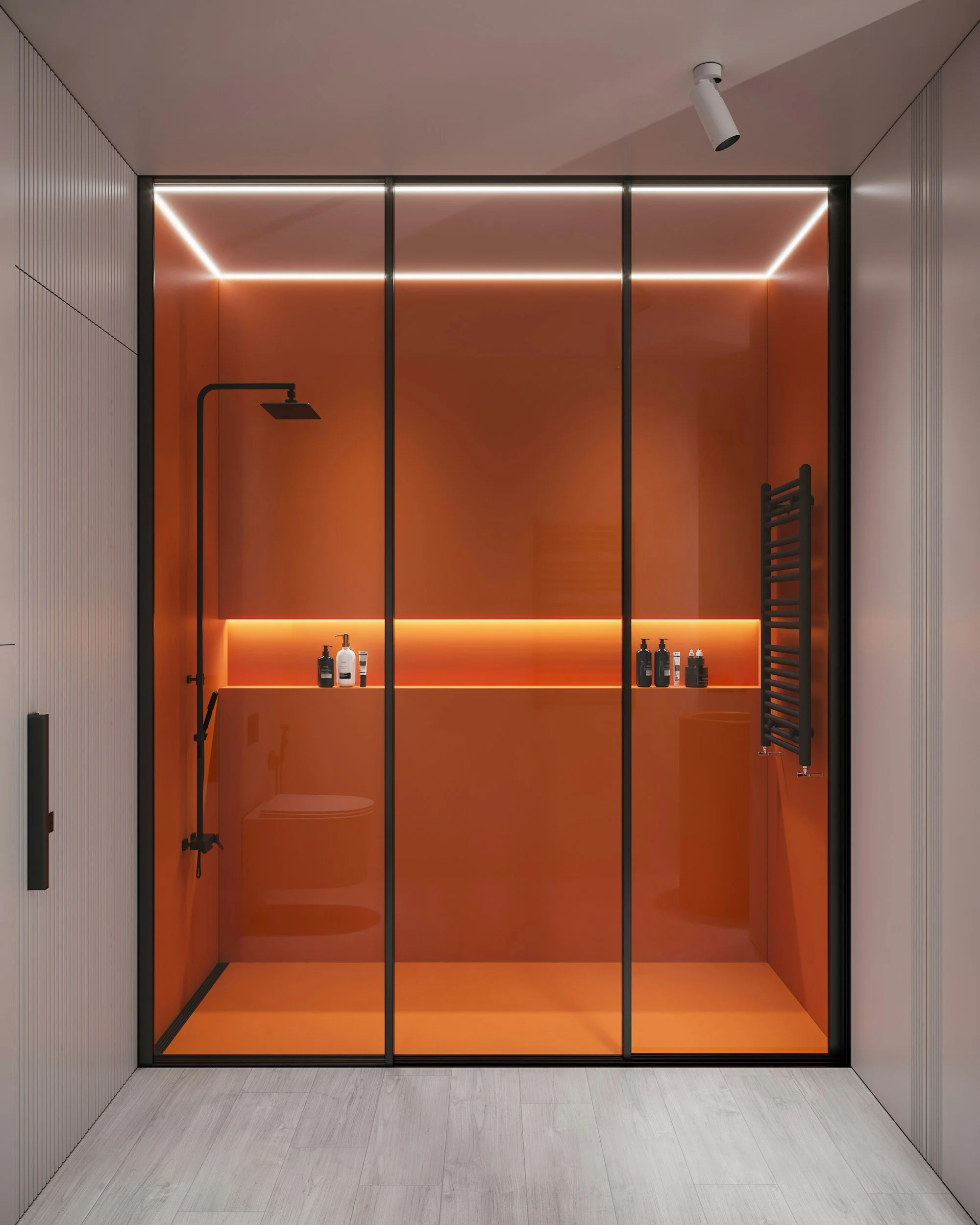 Modern walk-in shower with orange walls, black fixtures, and built-in shelving holding shampoo and soap bottles. Glass door with black frames and built-in LED lighting along the top. Formed Solid Surface