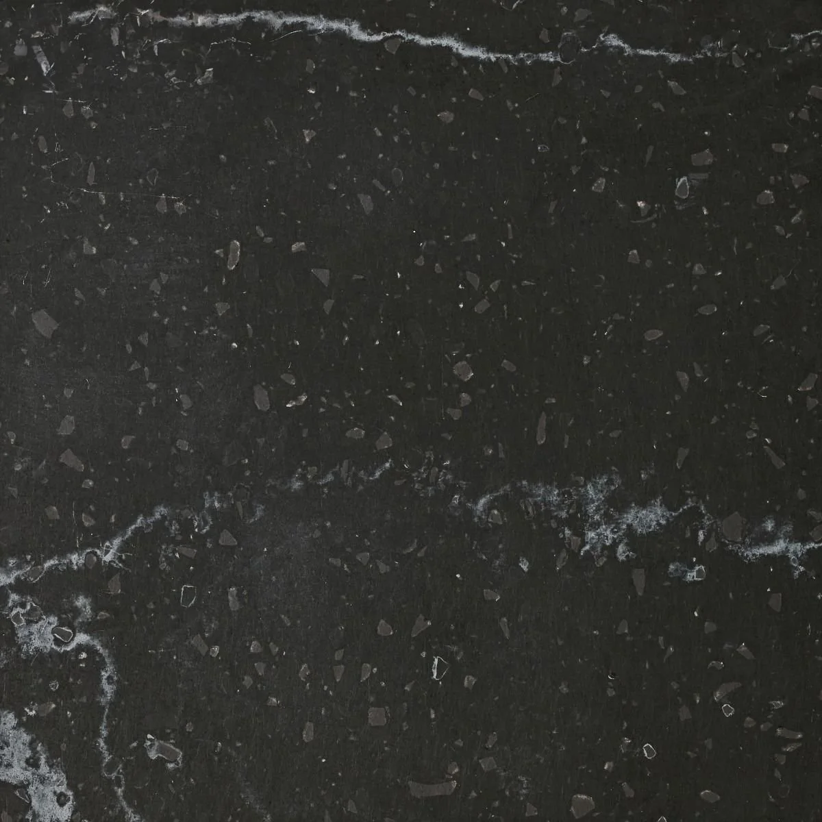Close-up photograph of a black granite Solid Surface with small reflective mineral specks and streaks of lighter color.