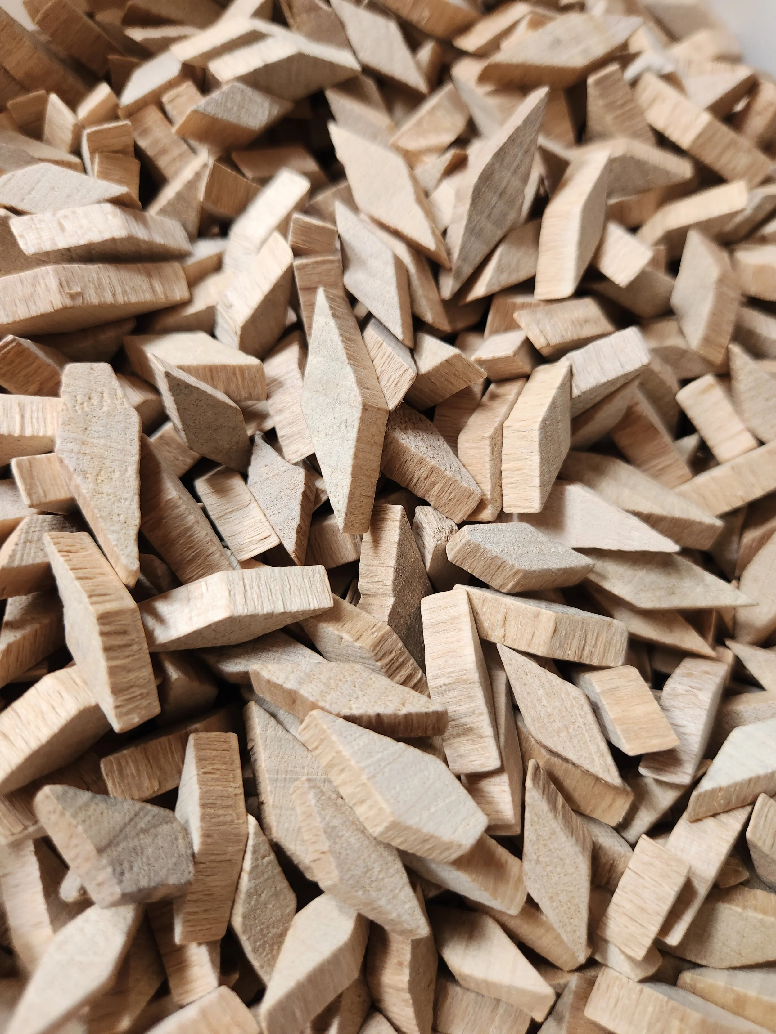 Close-up of numerous small, light-colored wooden pieces with various shapes and angular cuts.