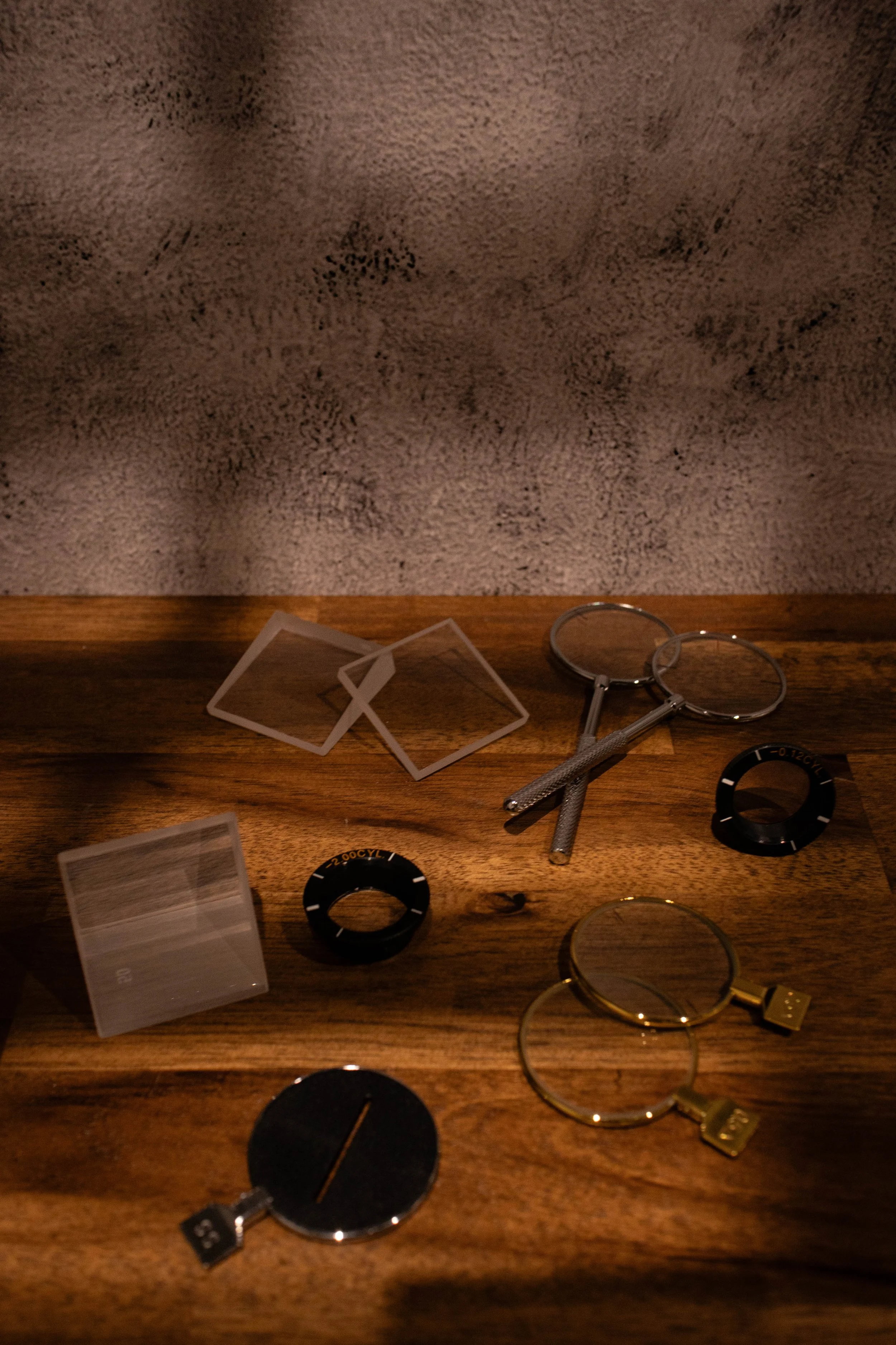 Various watch parts and tools on a wooden surface, including watch dials, bezels, and magnifying glasses.