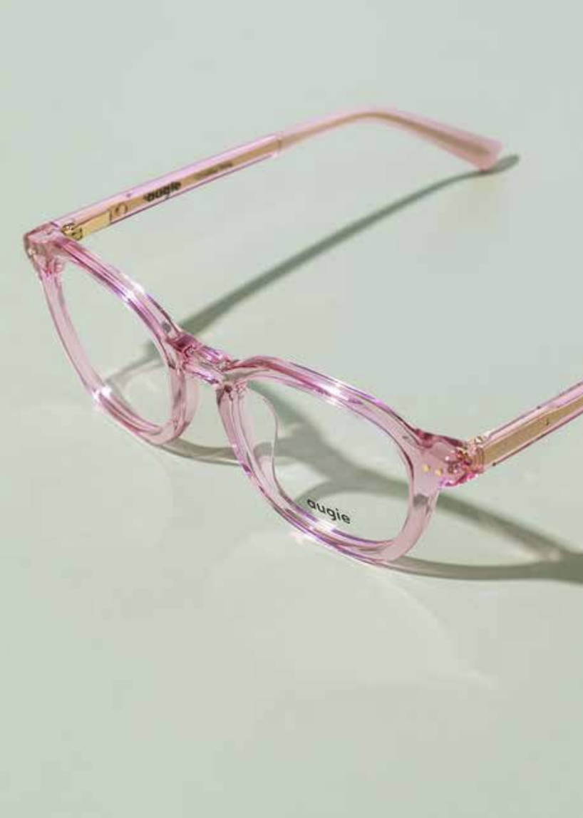 Pink transparent eyeglasses on light green surface