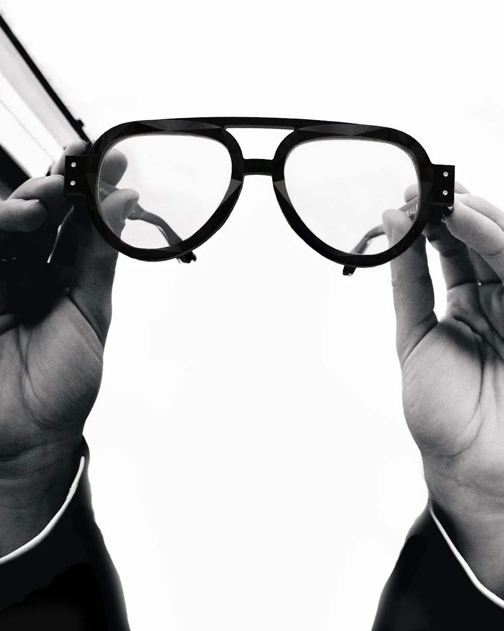 Hands holding up a pair of dark sunglasses against a white background.