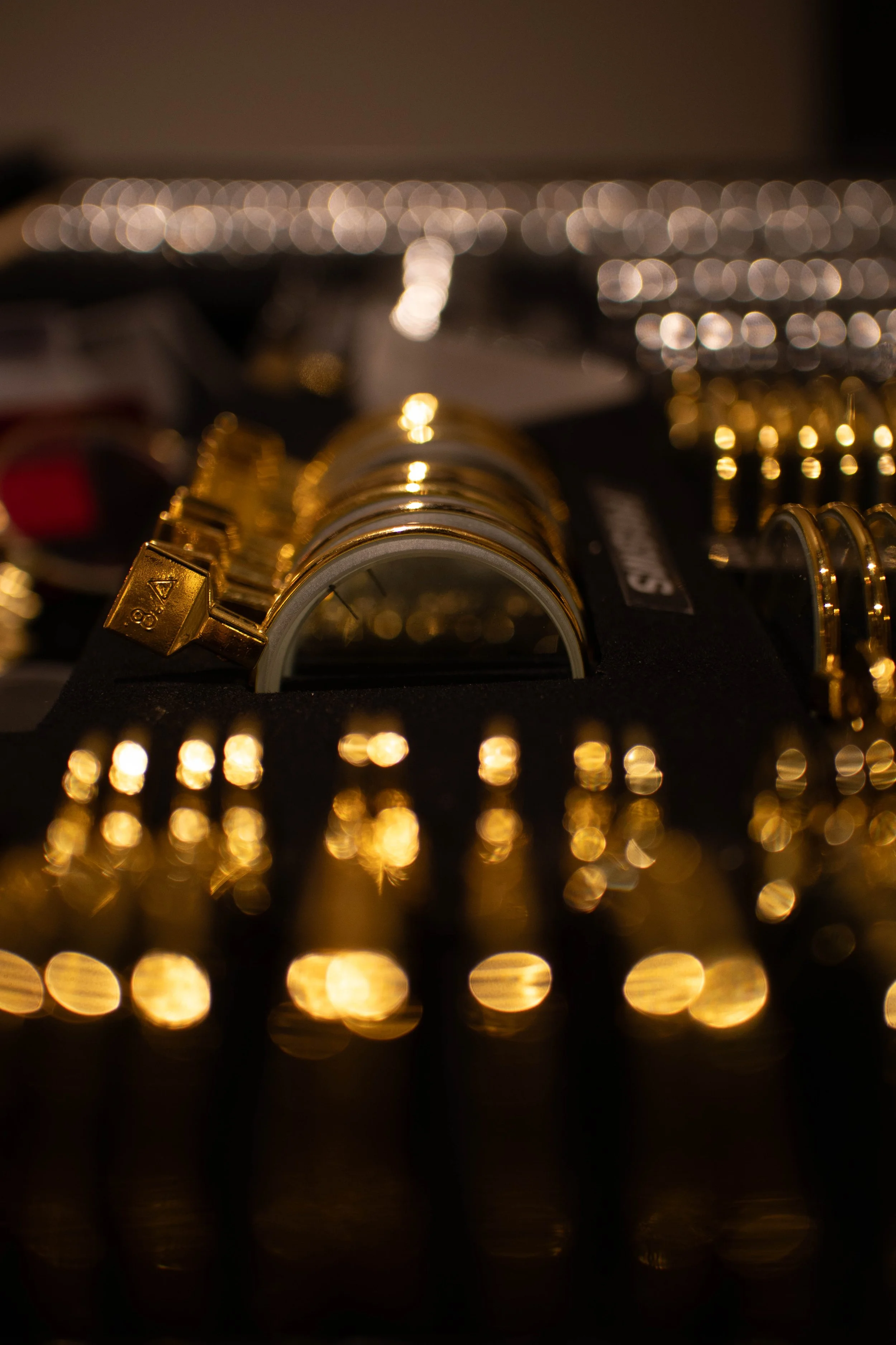 Close-up of a collection of gold-colored rings or bracelets, with a blurred background of bokeh lights.