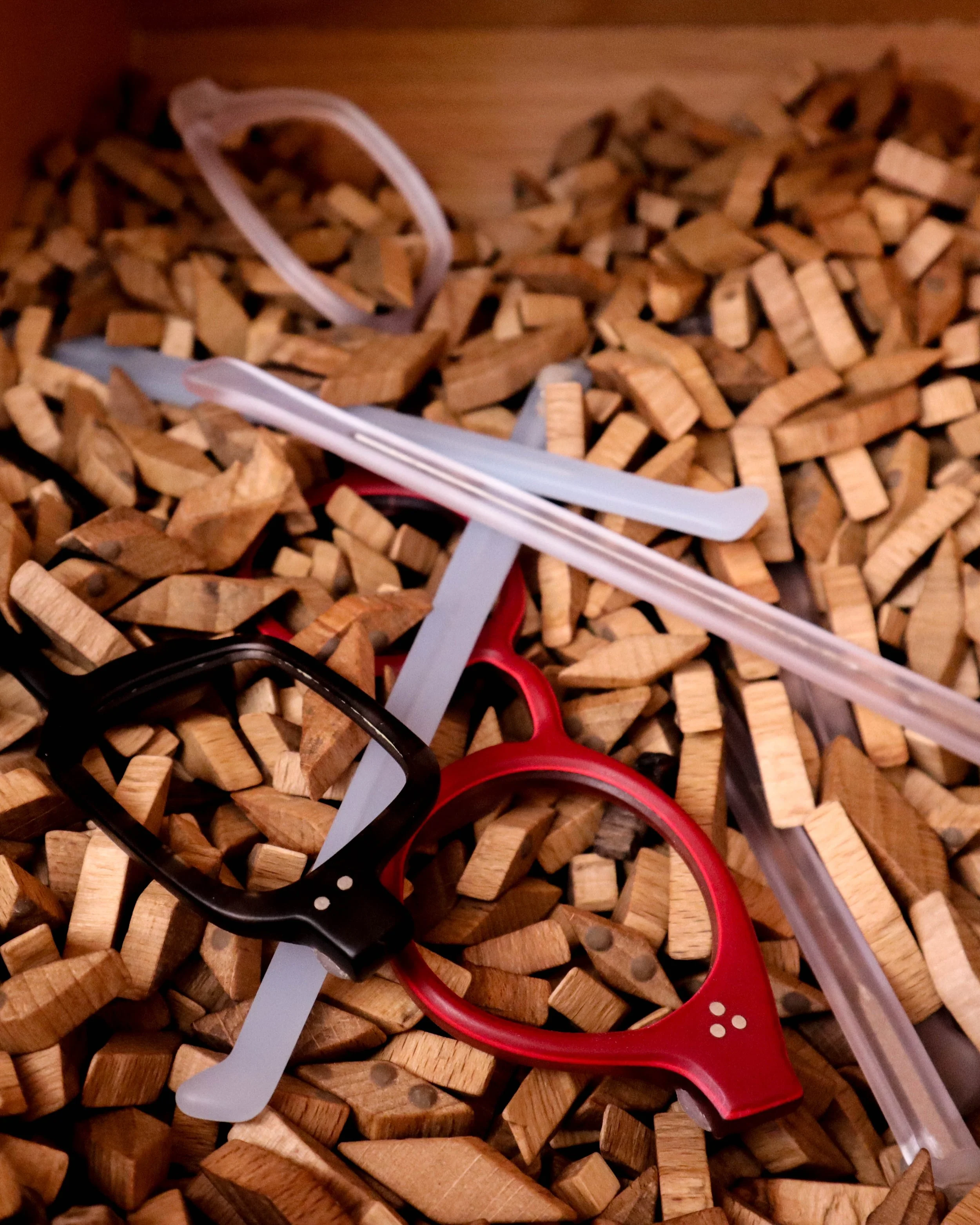 Colorful plastic slingshots resting on chopped wood pieces.