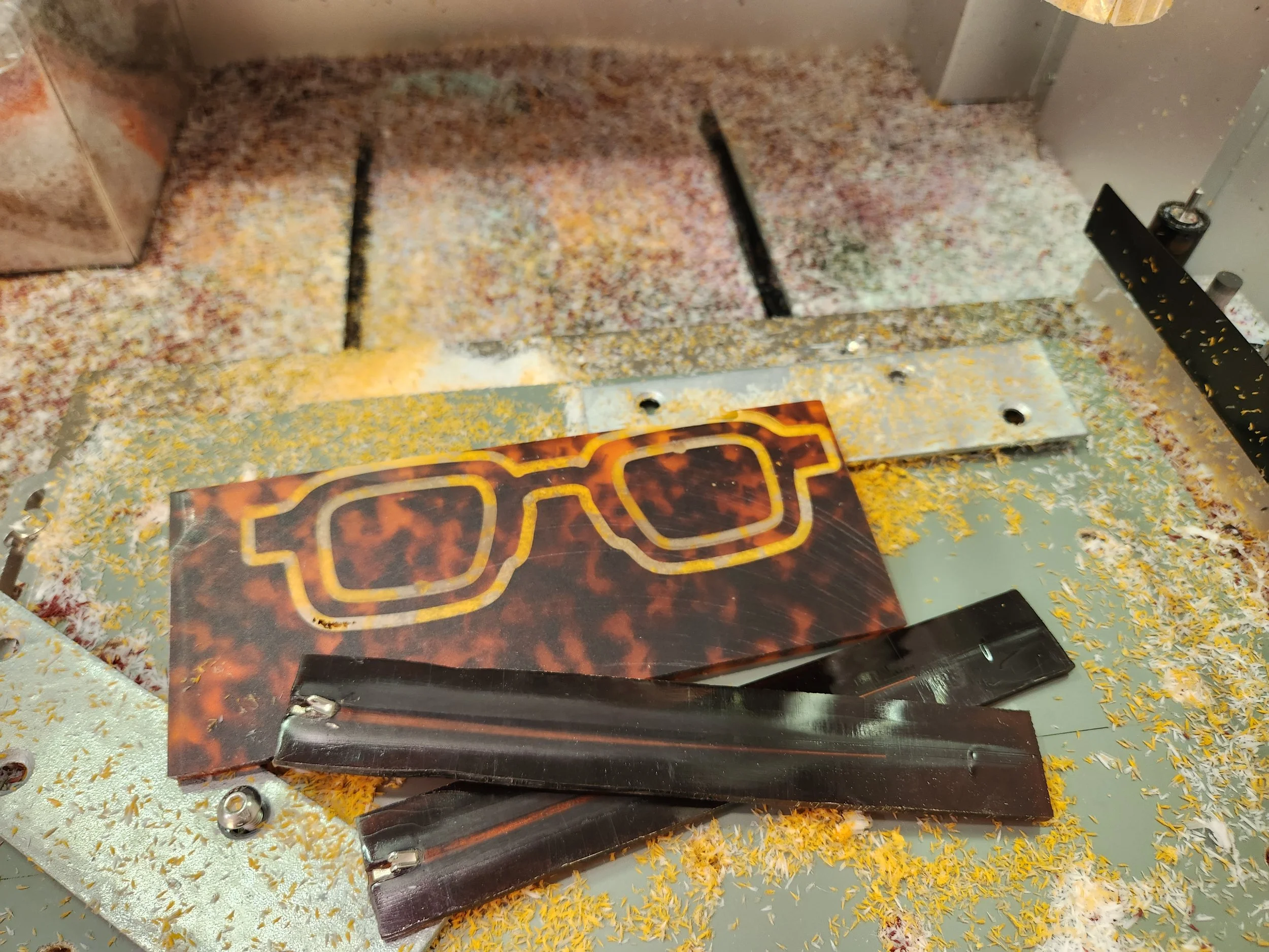 A slot machine with a fire theme, featuring a pair of sunglasses with a fiery design on the screen, surrounded by yellow and orange confetti or shredded paper.