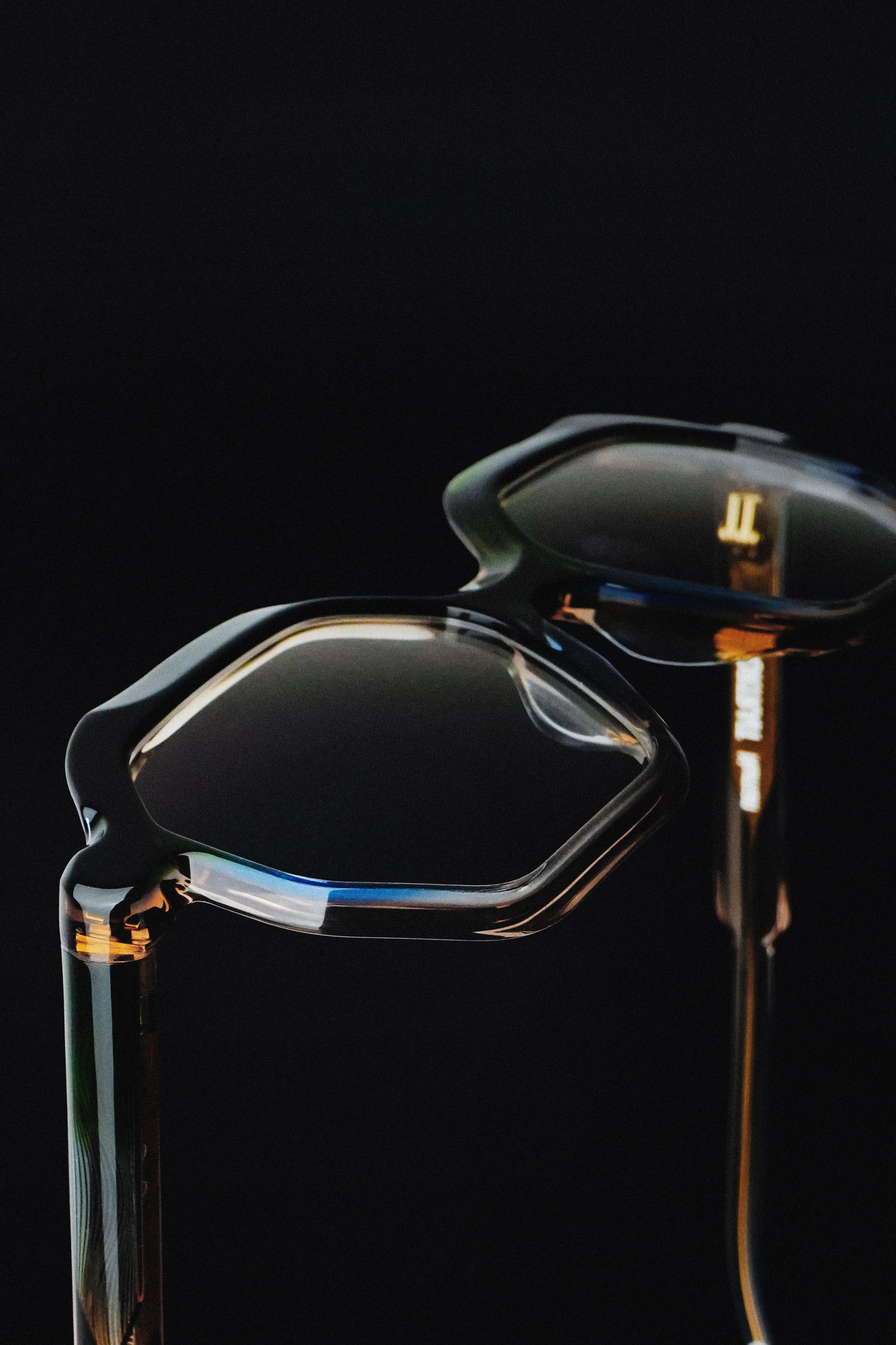 Close-up of two modern, reflective golf irons standing vertically against a black background.