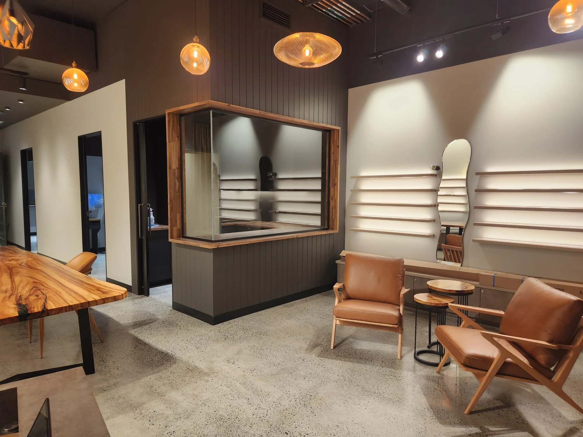 Interior of a modern, stylish meeting or lounge area with wooden tables, leather chairs, decorative wall panels, and warm hanging lights.