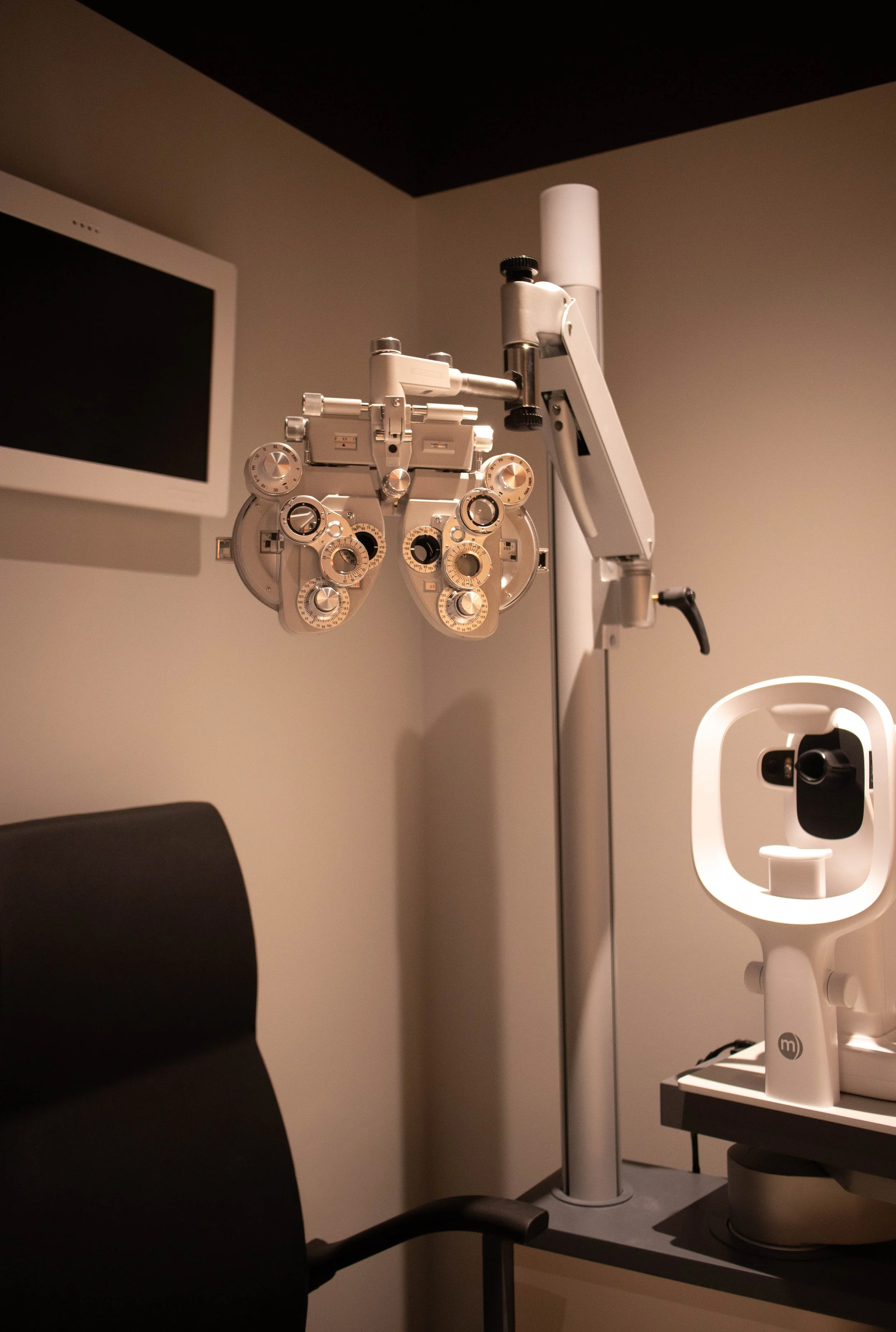 Medical examination room with an eye chart device and a chair in the foreground.