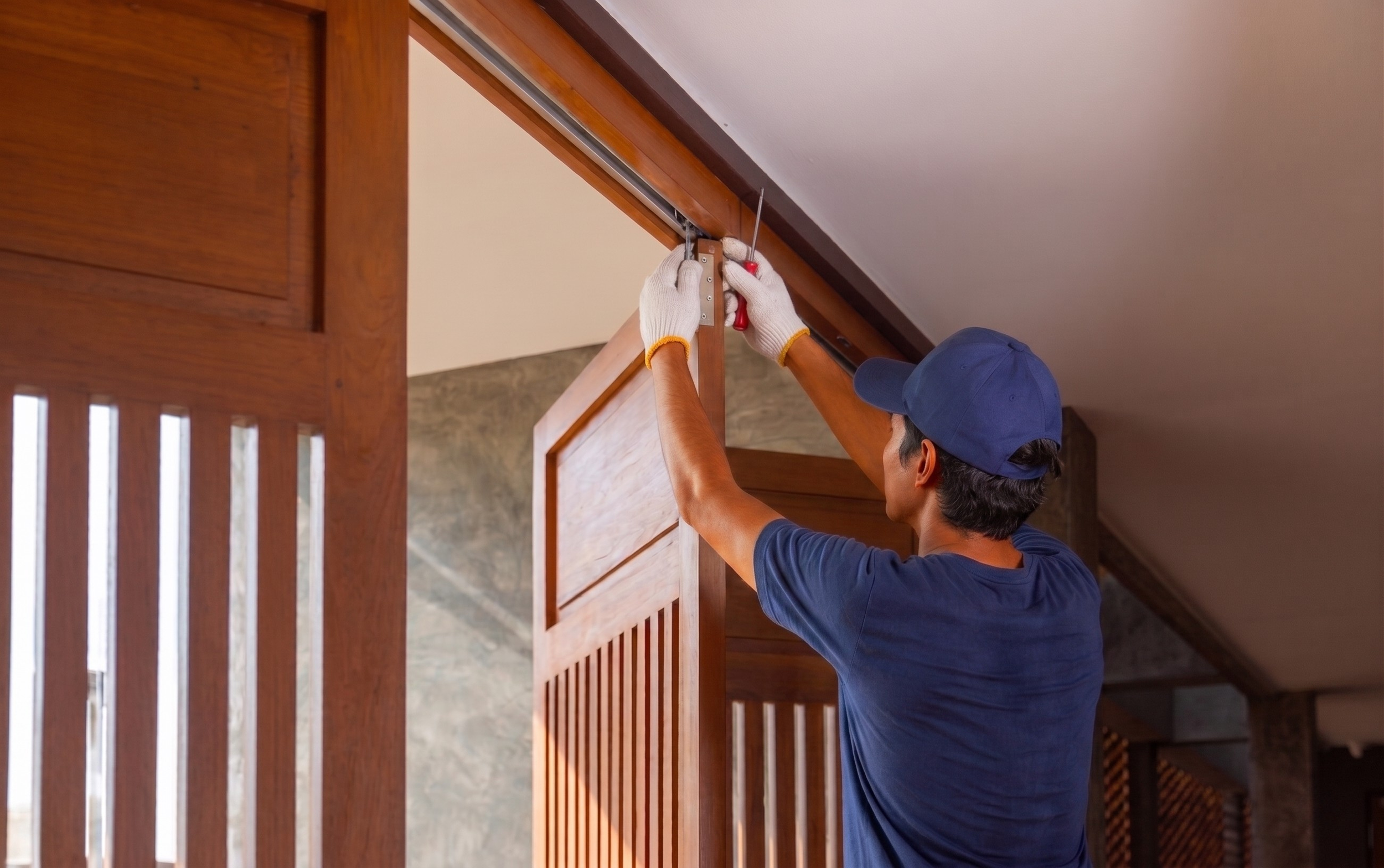 Technician installing door reinforcement hardware on residential front door