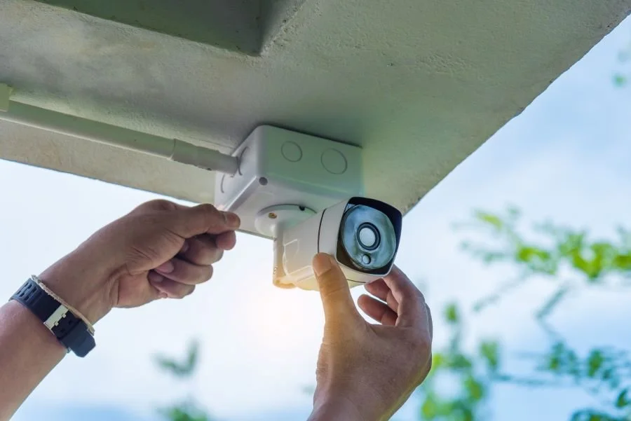 Person installing or adjusting a security camera on the exterior of a building