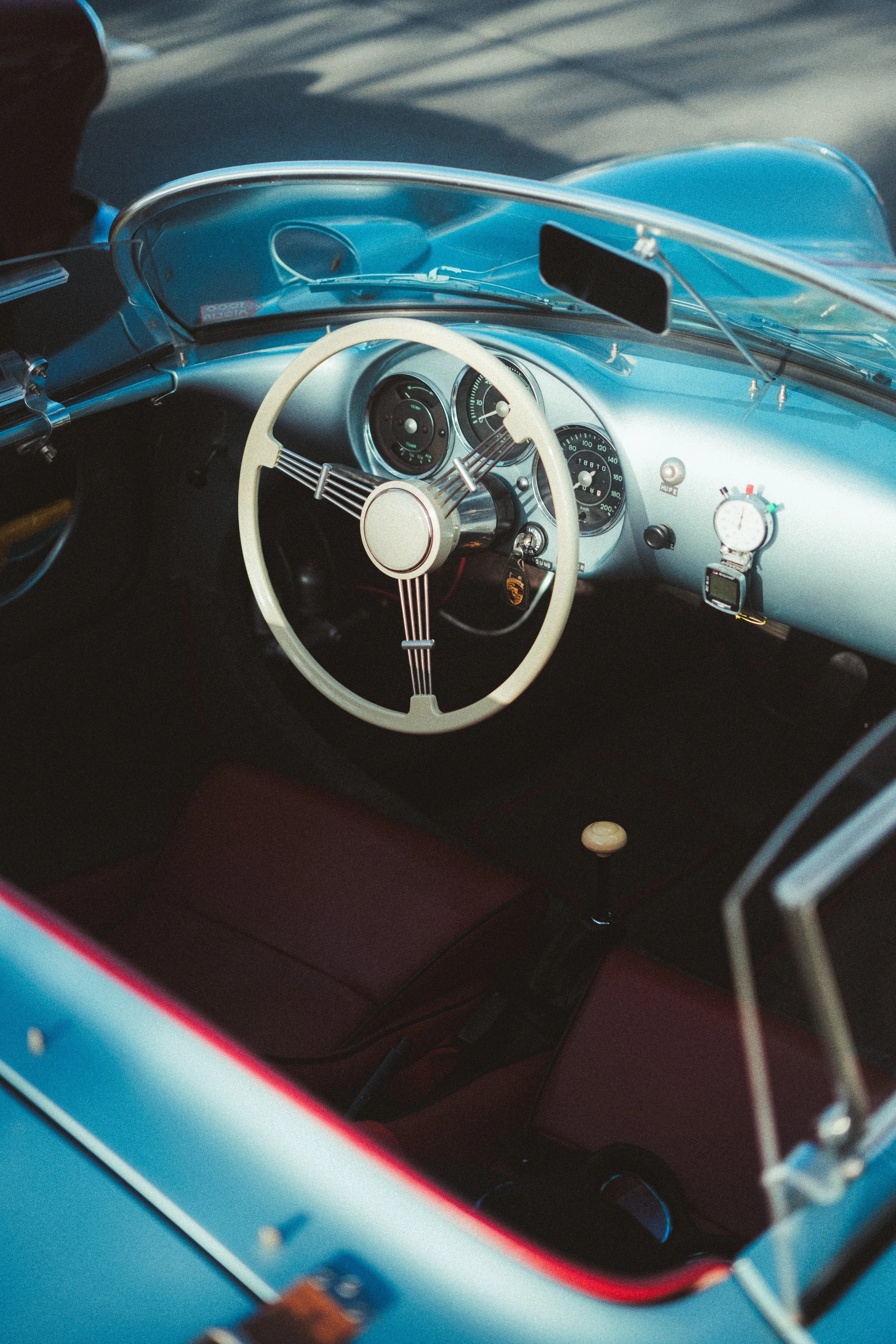 Interior view of a vintage blue convertible car, showing the dashboard with analog gauges and white steering wheel.
