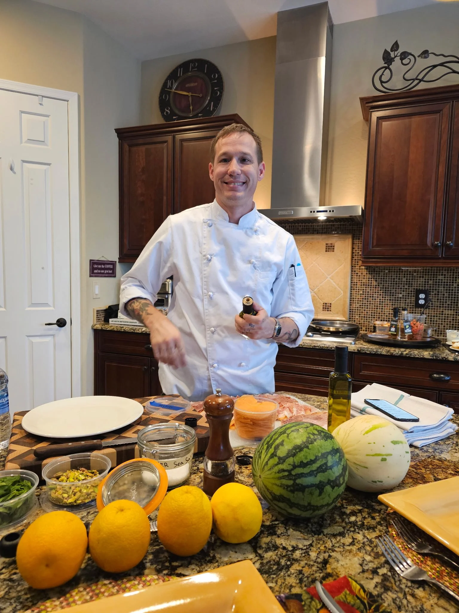Chef Mitch Bell smiling in a home kitchen surrounded by fresh produce.