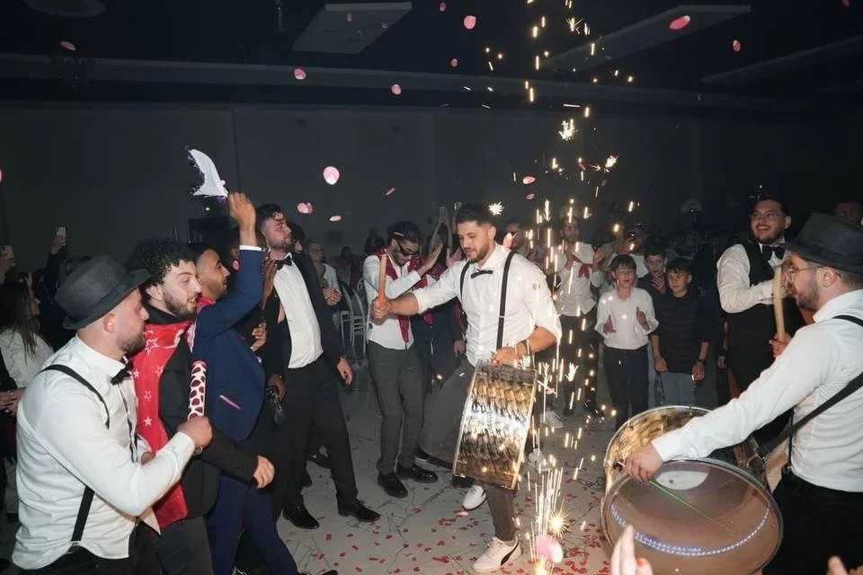 People celebrating at a party with sparklers and fireworks, dressed in formal and semi-formal attire, with mood of excitement and joy.
