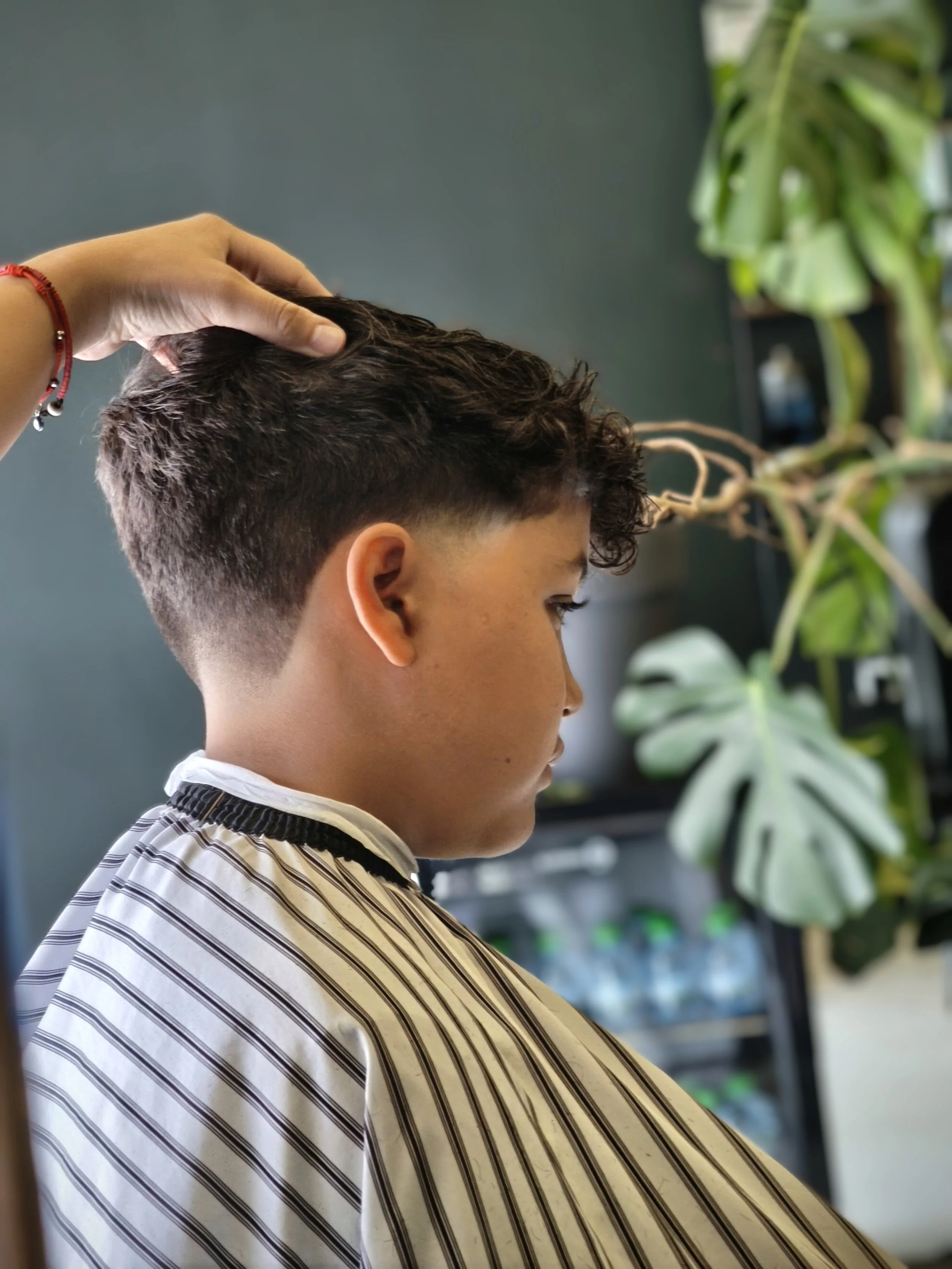 A person with short curly hair getting a haircut at a salon.