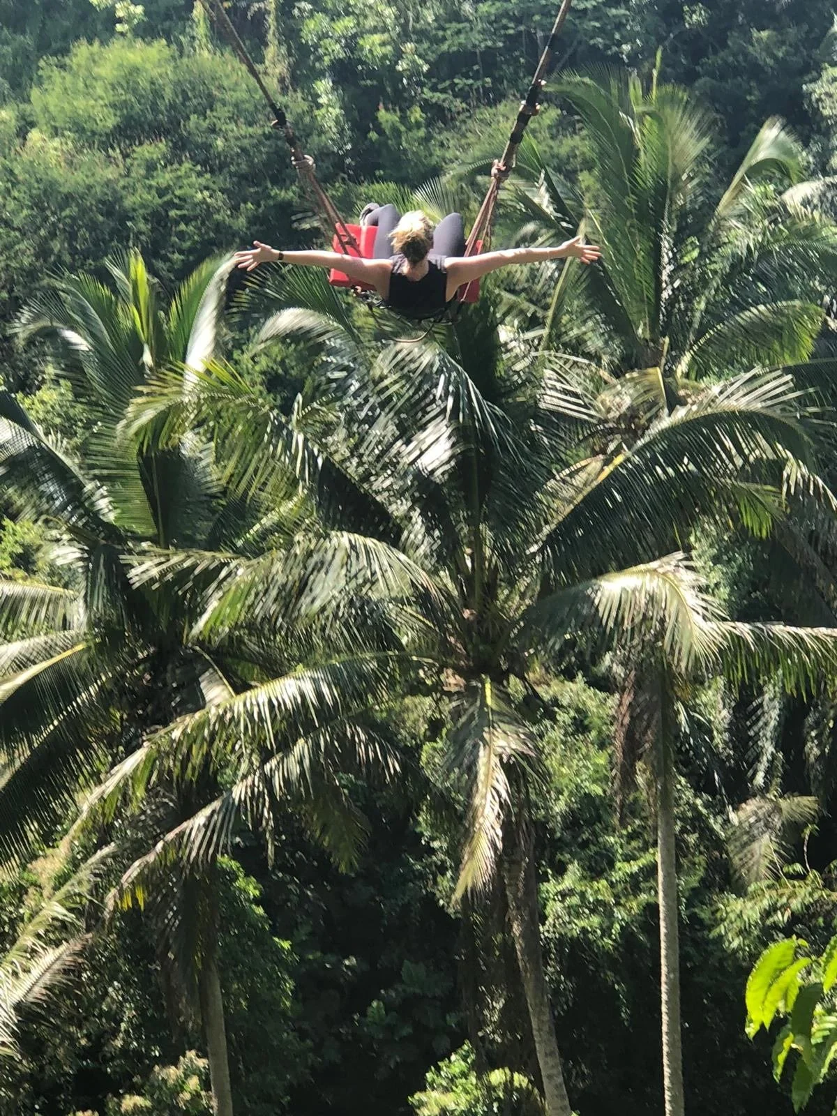 Abby on a swing in Bali arms outreached