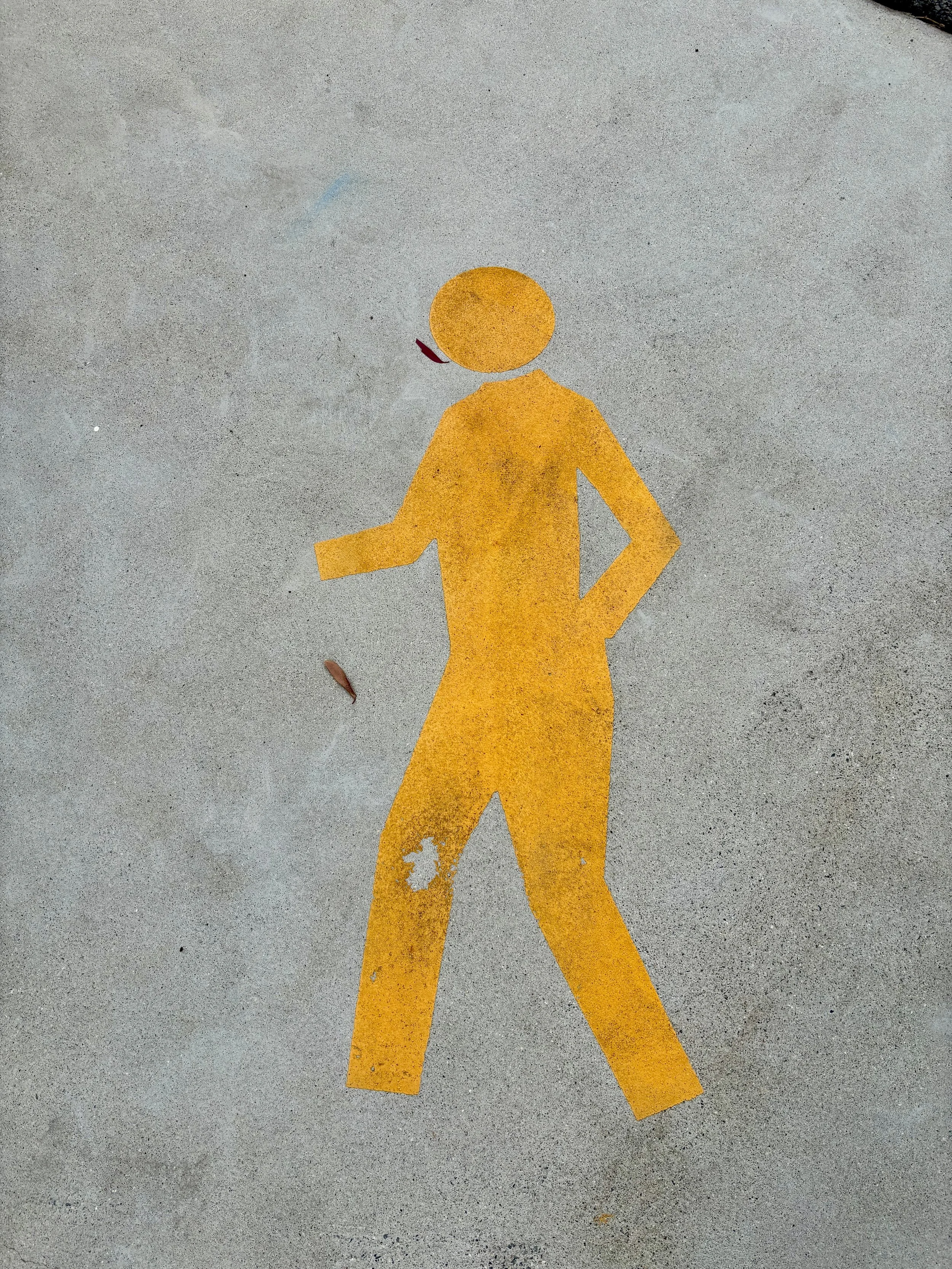 Yellow painted walking person symbol on concrete sidewalk - pressure cleaning Cairns